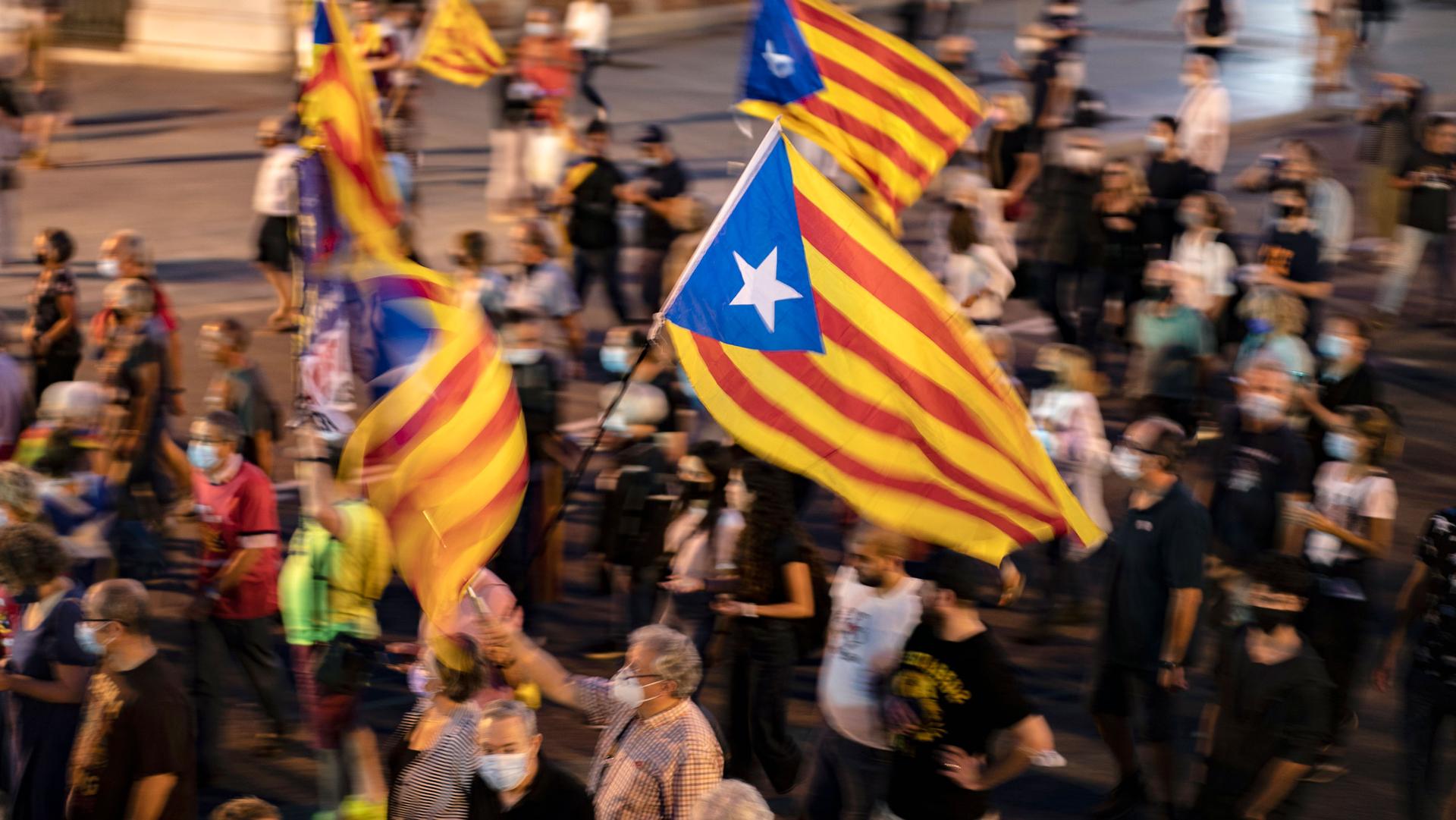People hold a Catalonian independence flag, as they march during a demonstration to mark the fourth anniversary of a failed independence referendum, in Barcelona, Spain, late Friday, Oct. 1, 2021. 