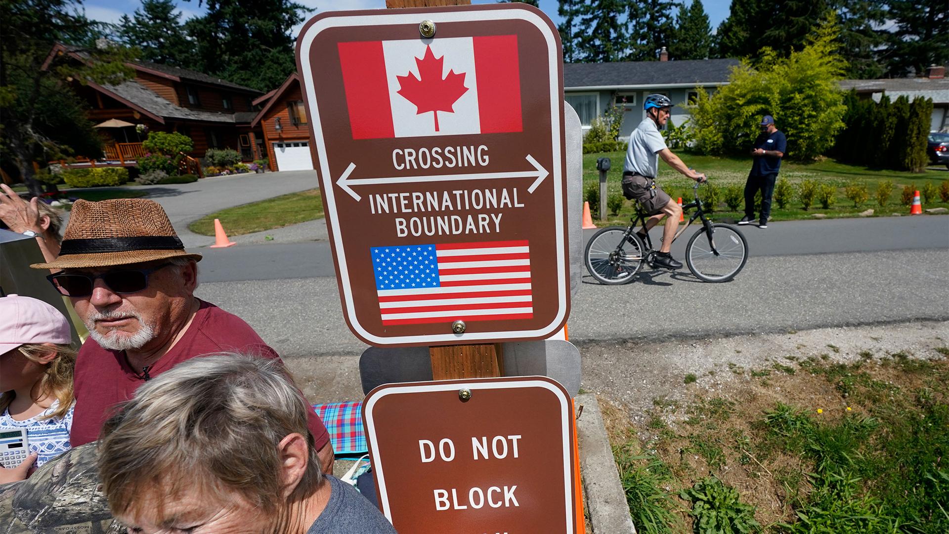 A family visits across the U.S.-Canada border at the Peace Arch Historical State Park as a cyclist rides past on the Canadian side, in Blaine, Wash.