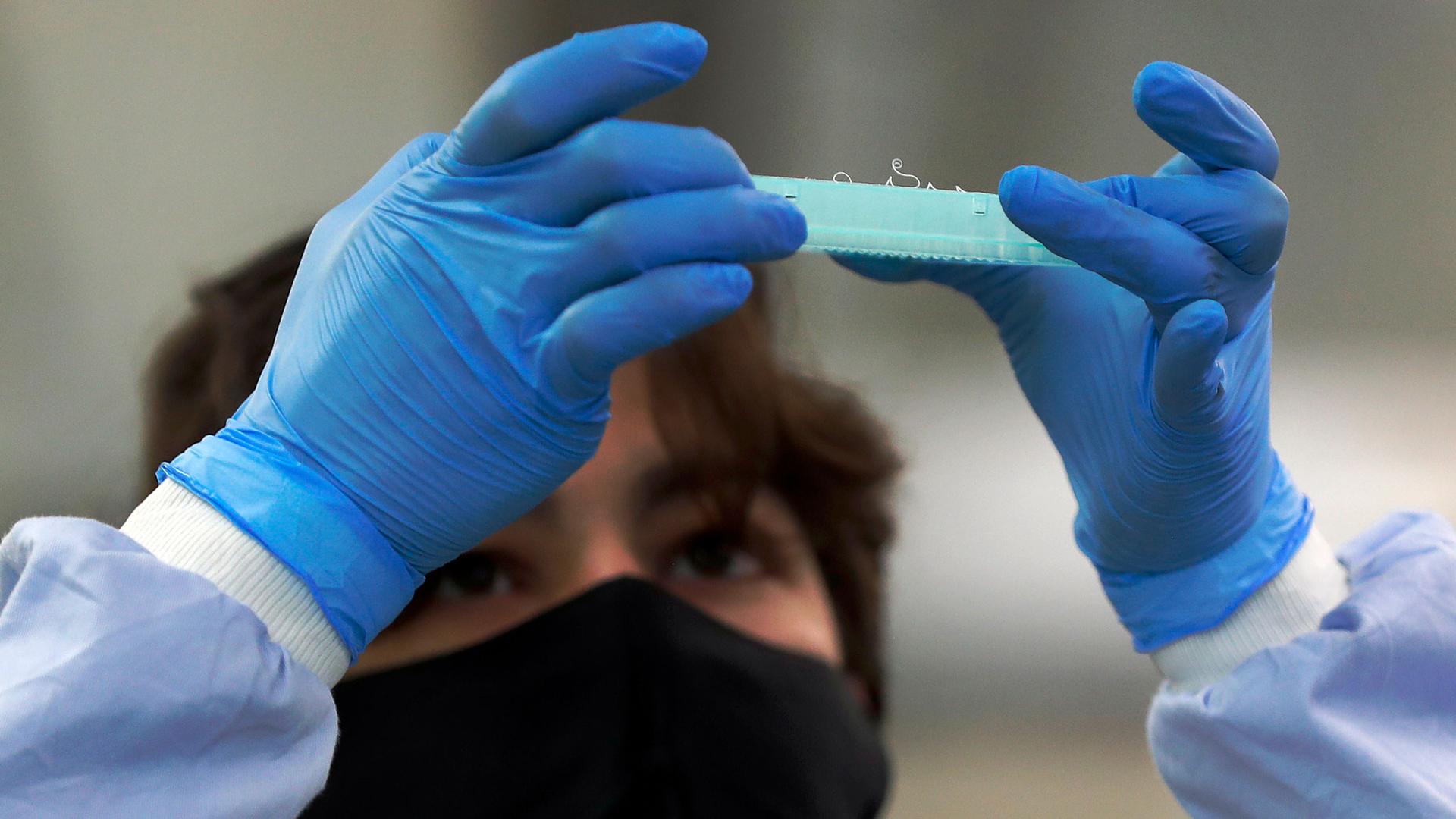 A lab assistant looks at an assay plate to prepare sequencing at the Wellcome Sanger Institute that is operated by Genome Research in Cambridge, Thursday, March 4, 2021. 