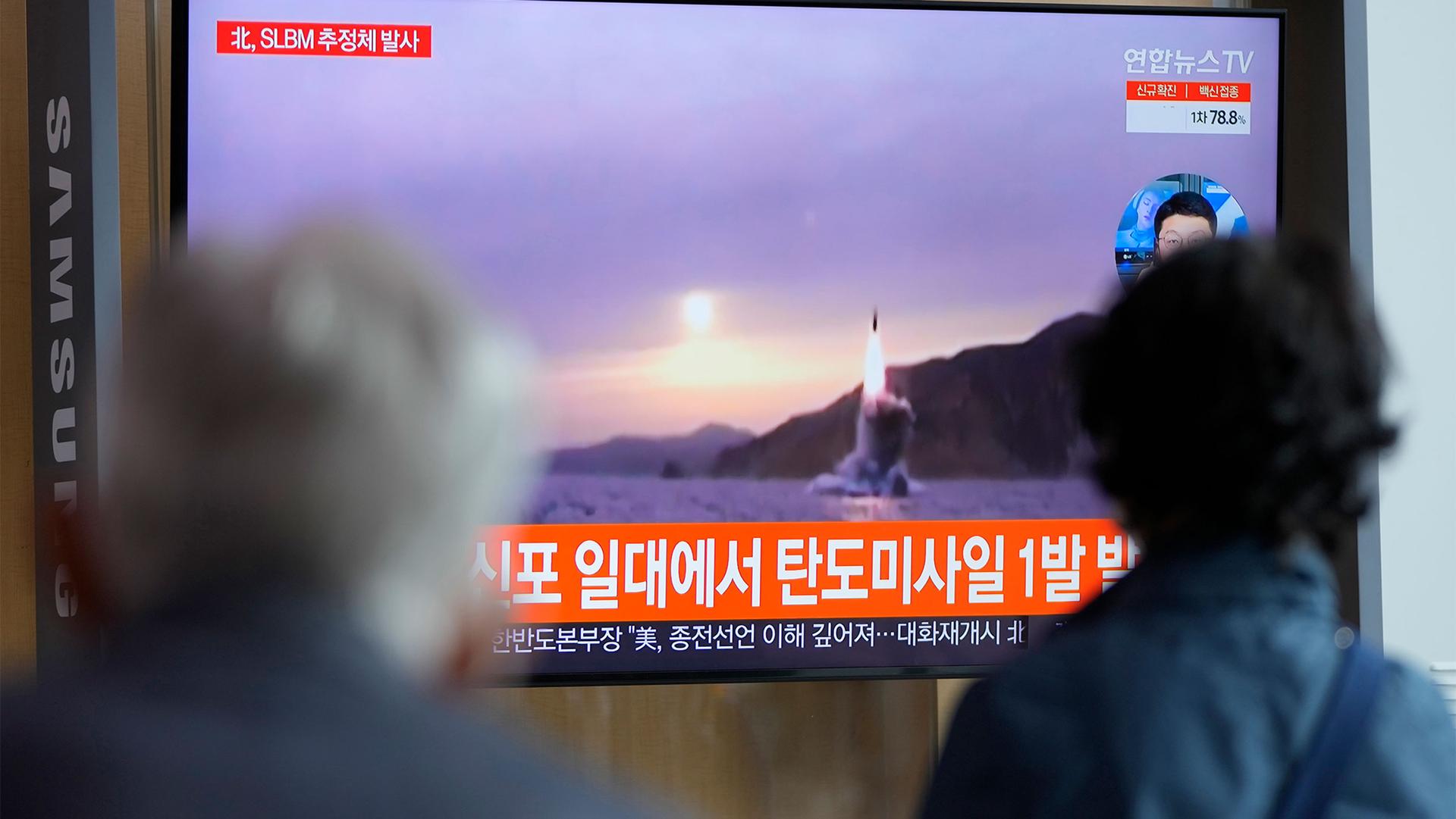 People watch a TV screen showing a news program reporting about North Korea's missile launch with file footage at a train station in Seoul, South Korea
