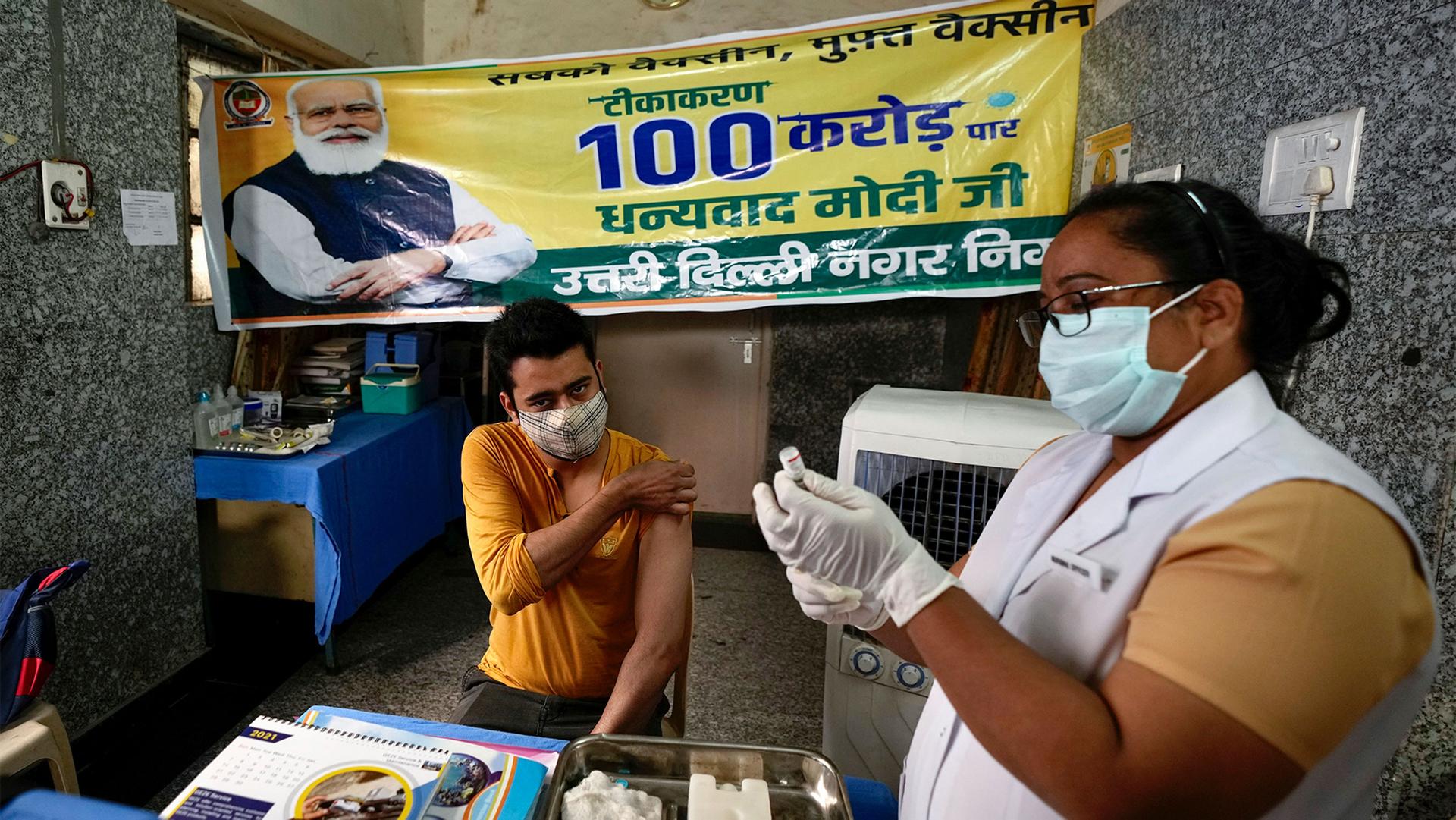 A health worker inoculates a man next to a banner thanking Prime Minister Narendra Modi for 1 billion doses of COVID-19 vaccine at a government hospital in New Delhi, India