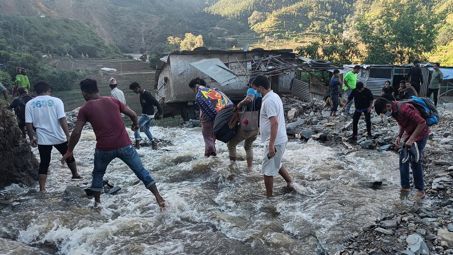 People wade past a flooded area in Dipayal Silgadhi, Nepal.