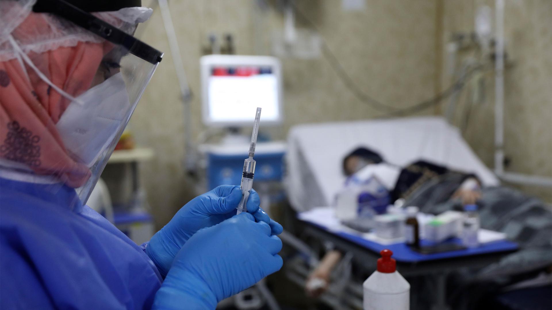 A nurse prepares a syringe for a patient infected with the coronavirus in the intensive care unit at the Syrian American Medical Society Hospital
