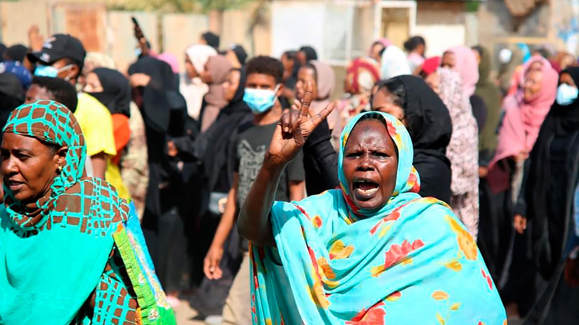 A pro-democracy protester wearing a turquoise blue scarf flashes the victory sign as thousands take to the streets to condemn a takeover by military officials, in Khartoum, Sudan, Oct. 25, 2021.