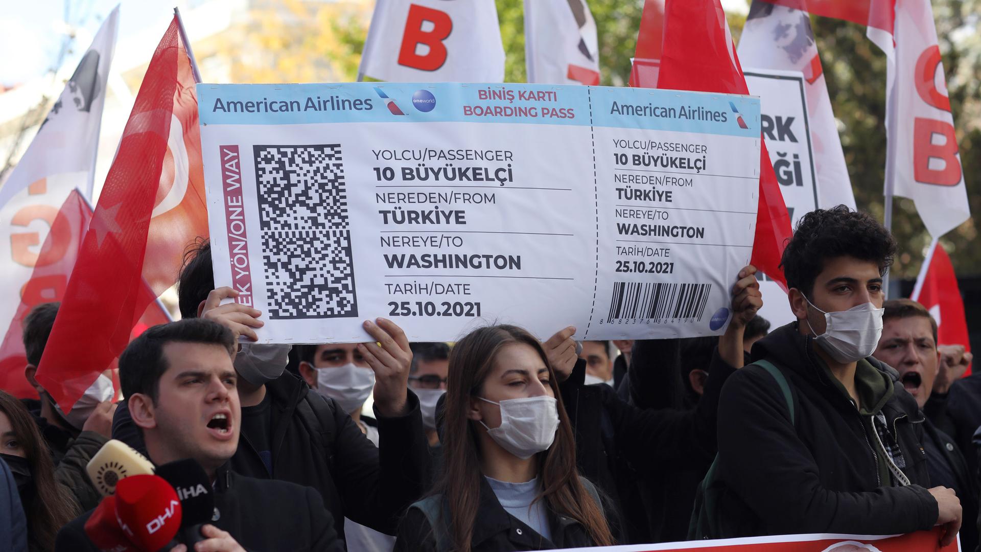 Members of a Turkish group hold a symbolic boarding pass for 10 foreign ambassadors as they stage a protest near the US Embassy to support Turkey's President Recep Tayyip Erdoğan, in Ankara, Turkey, Monday, Oct. 25, 2021. 