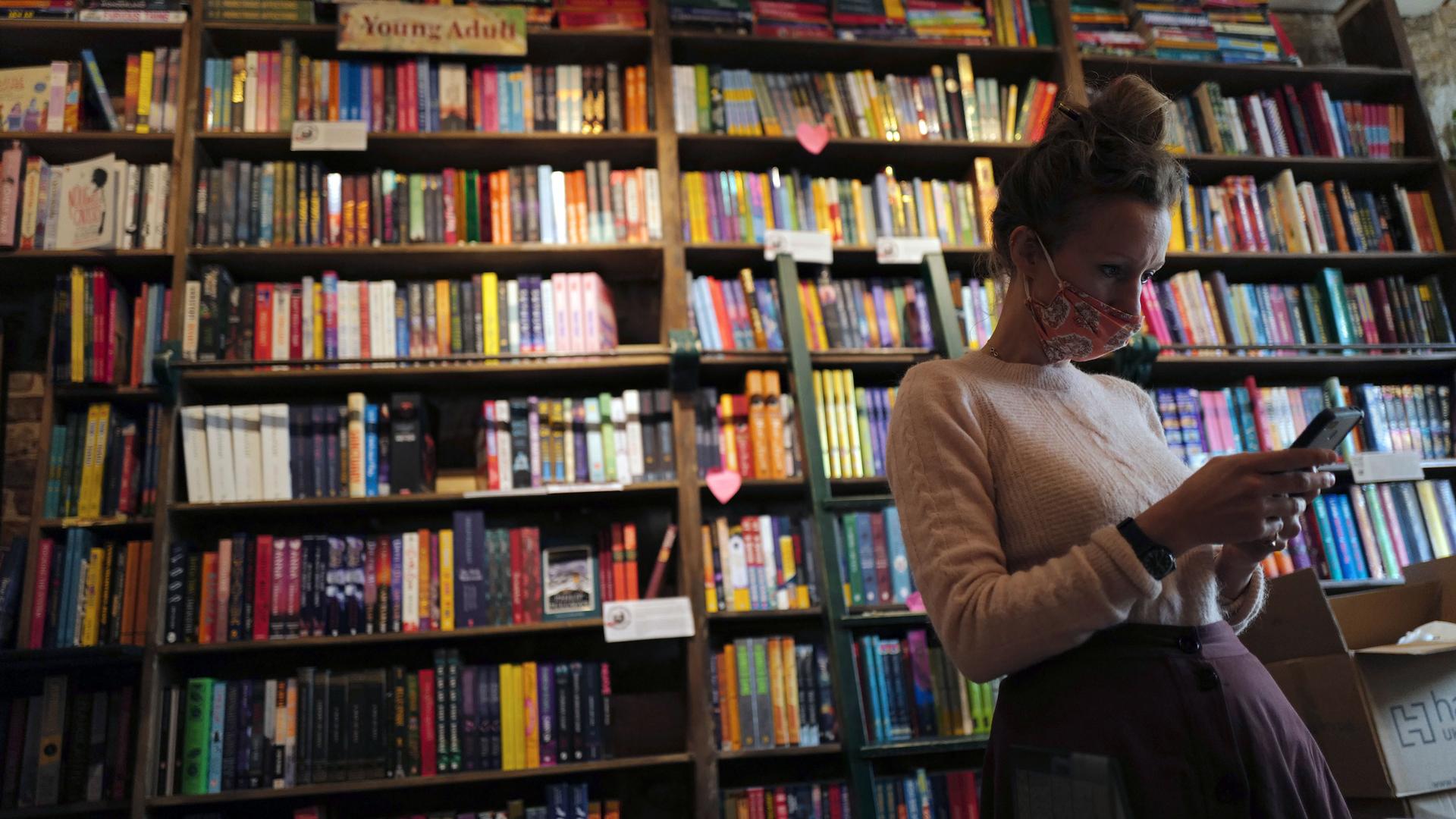 Sylvia Whitman, proprietor of the English and American literature Shakespeare and Co. bookstore, checks her messages on her phone in Paris, France, Thursday, Nov. 5, 2020.