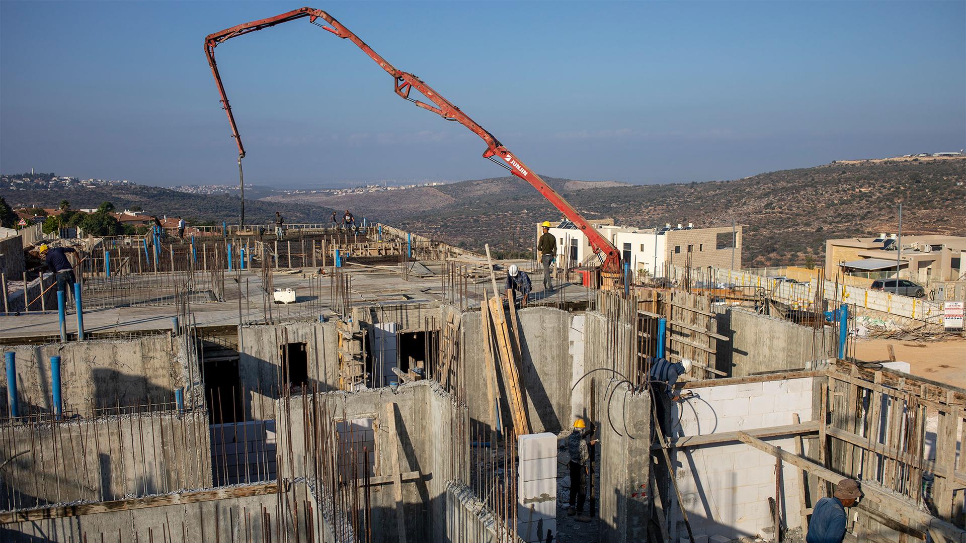 Palestinian laborers work building new houses in the West Bank Jewish settlement of Bruchin near the Palestinian town of Nablus