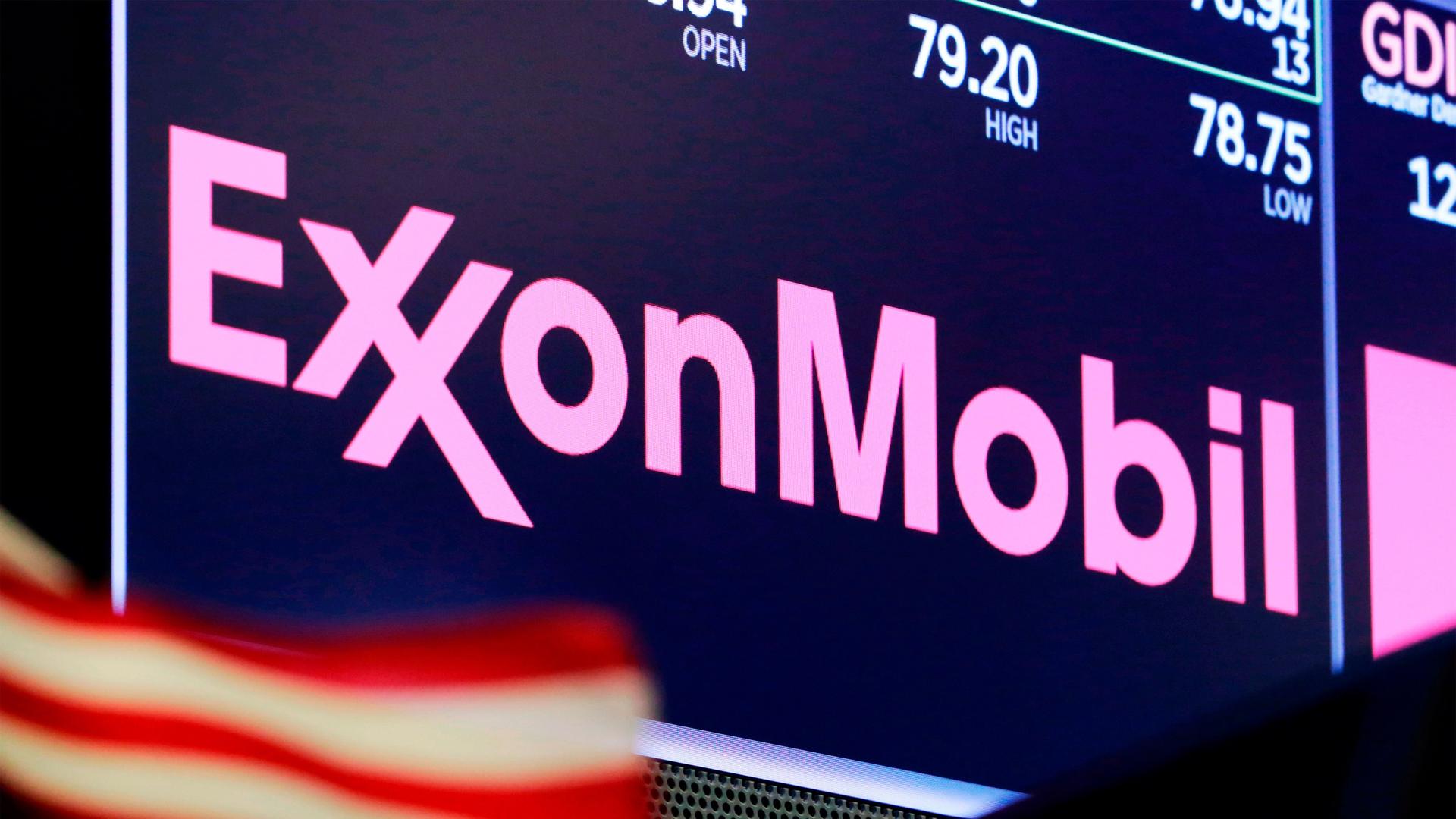 The logo for ExxonMobil appears above a trading post on the floor of the New York Stock Exchange