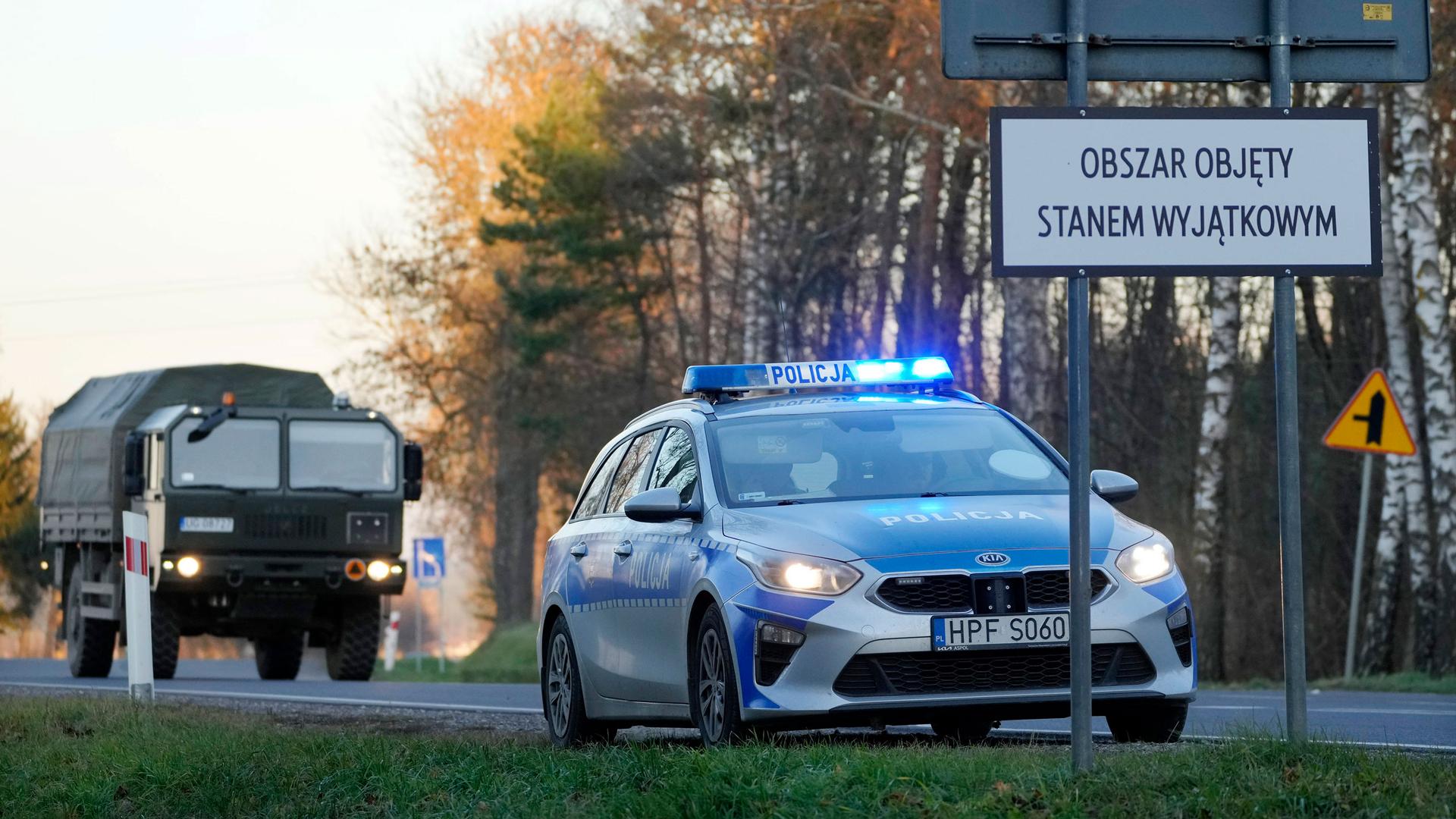 A Polish police car and a military truck are parked at a makeshift check point at the perimeter of the emergency state that covers a 1.9 mile-wide strip along the border with Belarus, Chreptowce near Kuznica, Poland, on Tuesday, Nov. 9, 2021.