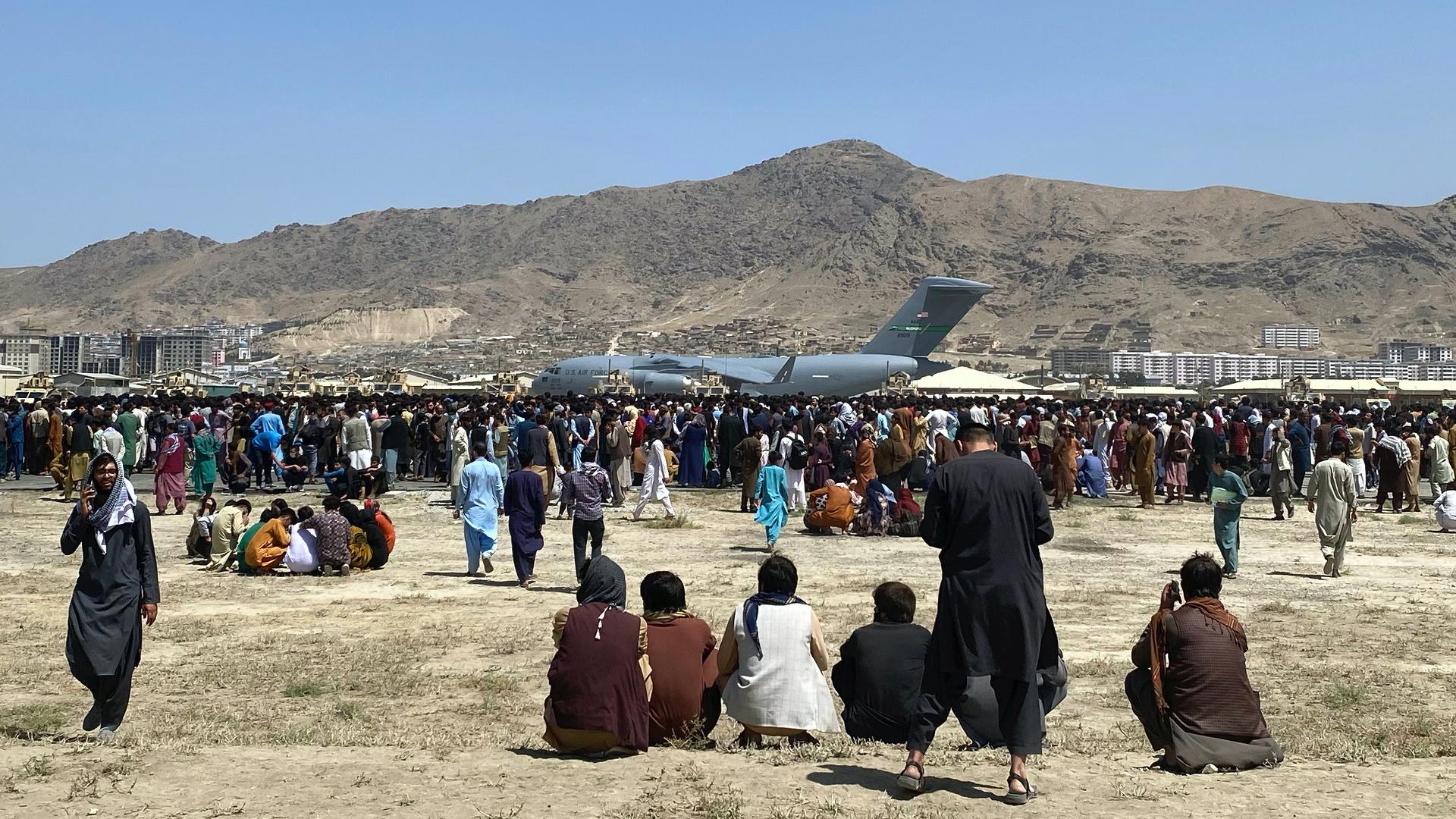 Hundreds of people gather near a US Air Force C-17 transport plane at the perimeter of the international airport in Kabul, Afghanistan, Aug. 16, 2021.