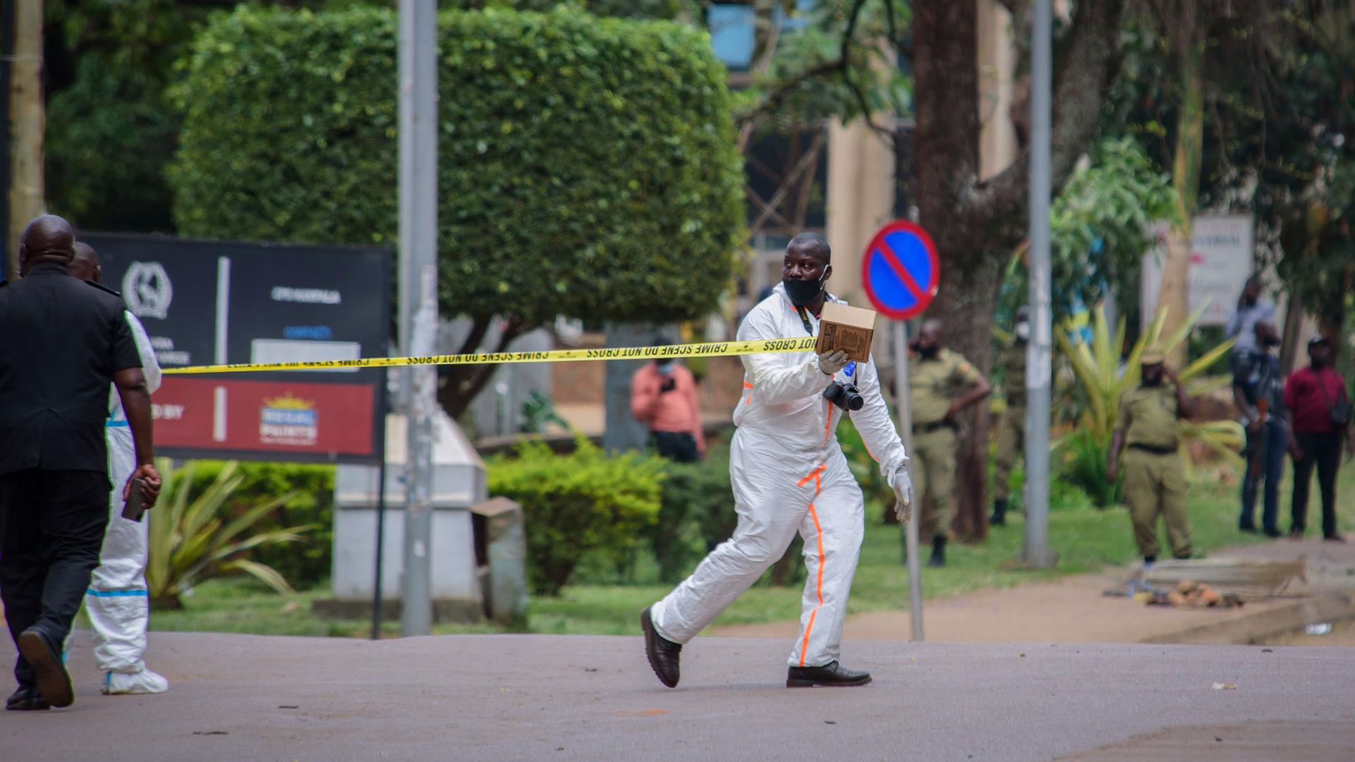 A forensics officer secures the scene of a blast next to the central police station in Kampala, Uganda, Tuesday, Nov. 16, 2021. 