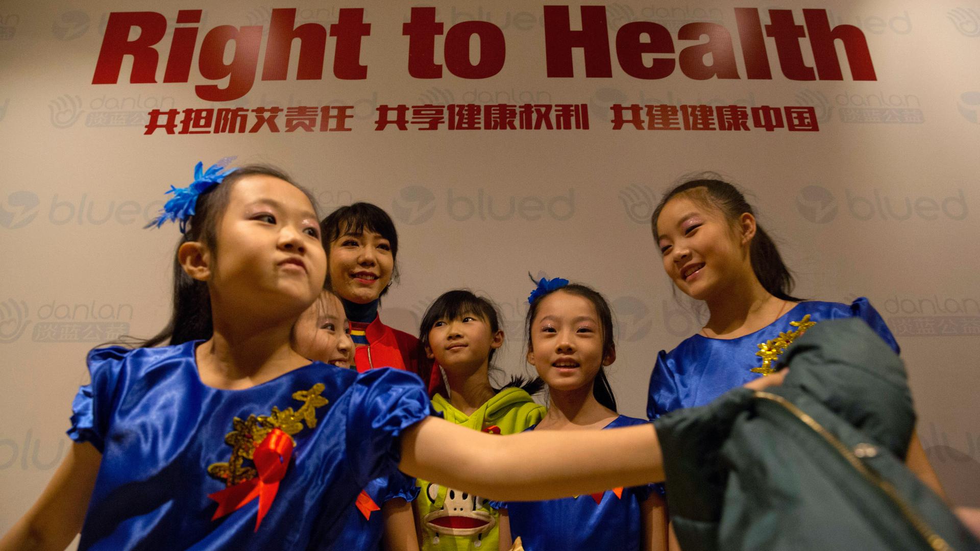 Chinese singer Wu Mochou, in red, poses for photos with young performers at an event to raise awareness ahead of World AIDS Day in Beijing, Nov. 14, 2017. The event was hosted by Danlan Public Welfare ahead of the 30th World AIDS Day to promote the use of