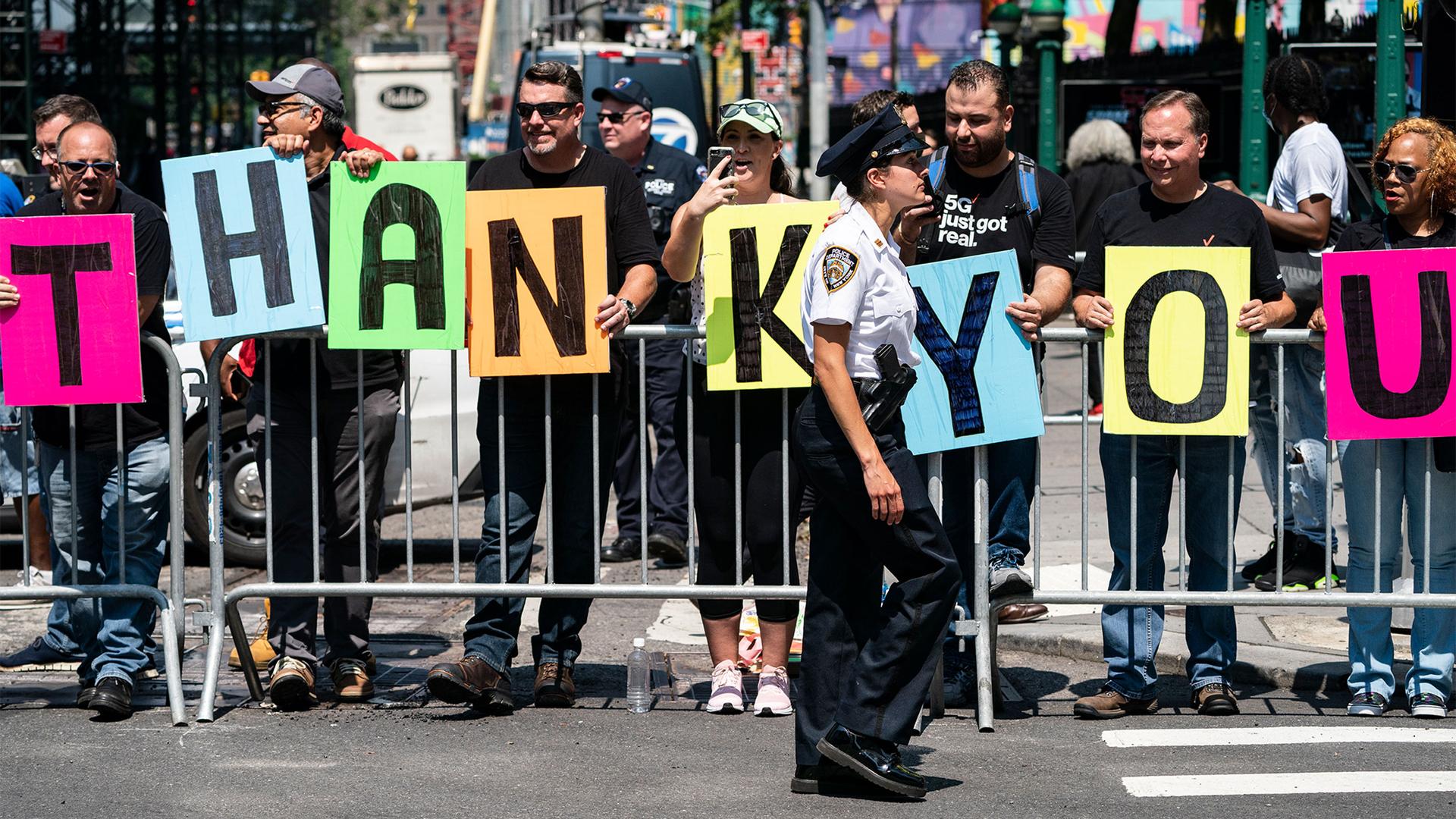 A line of spectators spell out the words "Thank You", as a New York City police officer marches through the Financial District during a parade honoring essential workers for their efforts in getting New York City through the COVID-19 pandemic, July 7, 202