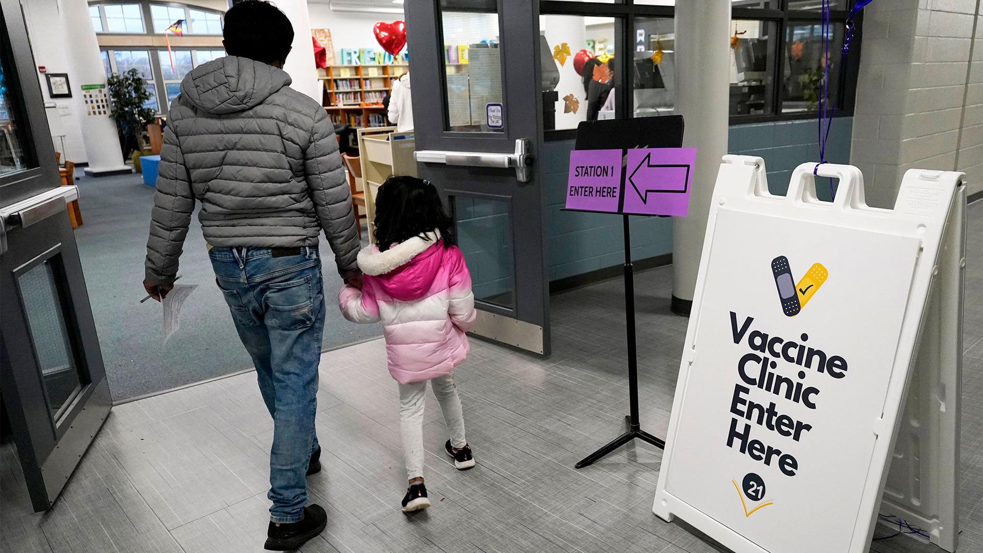 An information sign is displayed as a child arrives with her parent to receive the Pfizer COVID-19 vaccine for children 5 to 11-years-old at London Middle School in Wheeling, Ill.