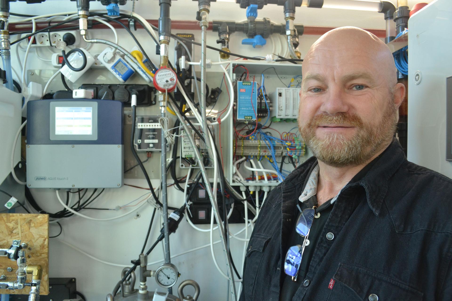Per Ericson stands in front of a wall of technological equipment to recycle grey water.