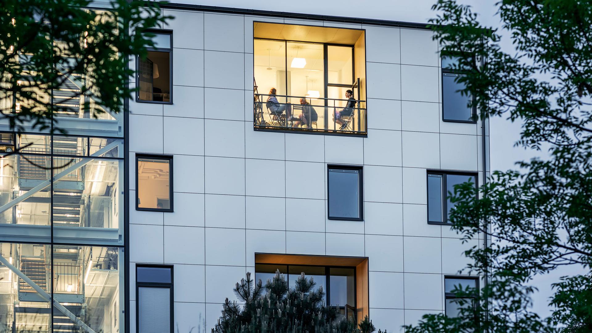 The white facade of the Living Lab in Sweden with a light on in the upstairs window. 