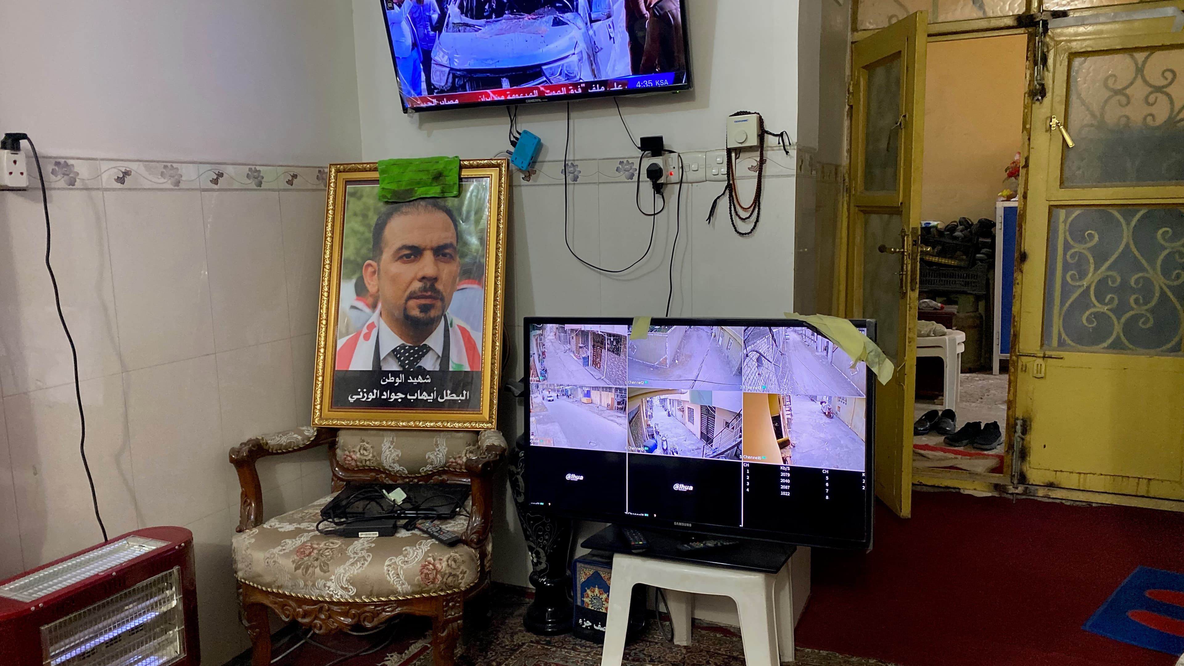 A portrait of slain Iraqi activist Ehab al-Wazni sits propped up in a chair in his family’s living room in Karbala, Iraq. Atop it is a rag of dried blood and next to it is a TV monitor with security camera footage, Dec. 7, 2021.