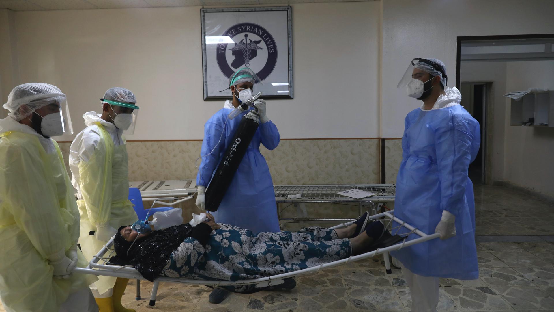 Medical workers carry a patient infected with the coronavirus on a stretcher at the Syrian American Medical Society Hospital, in the city of Idlib, northwest Syria, Sept. 20, 2021. 