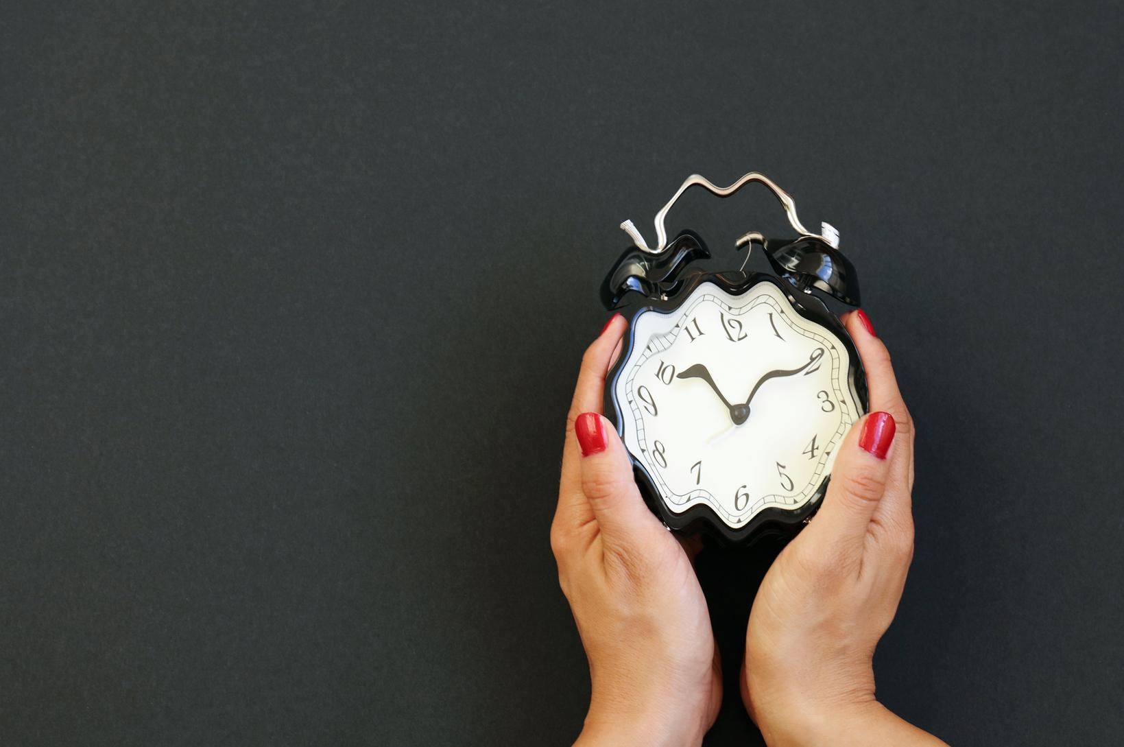A woman holding a distorted alarm clock 