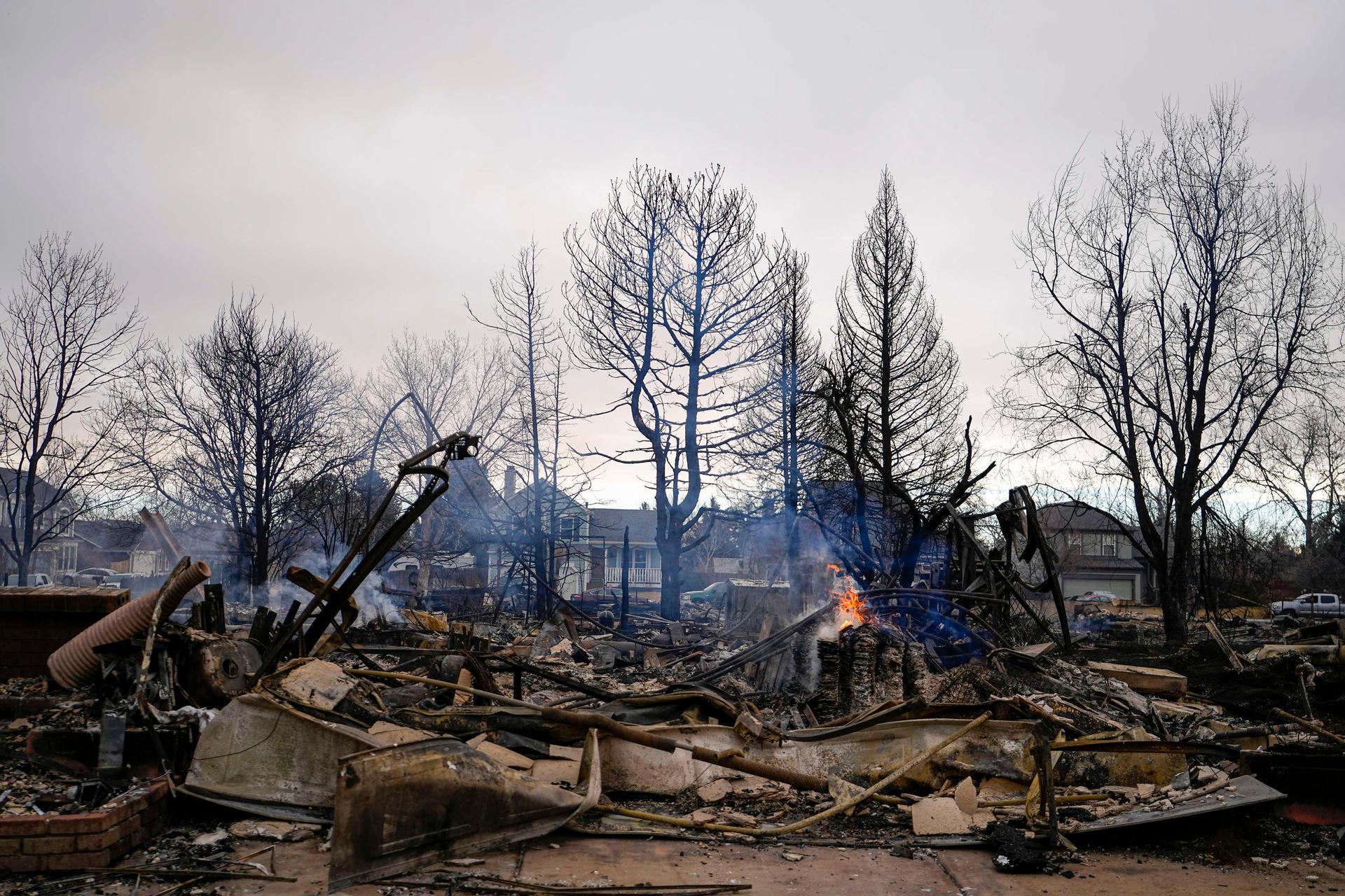 A fire still burns in a home destroyed by the Marshall Wildfire in Louisville, Colorado, Friday, Dec. 31, 2021. 