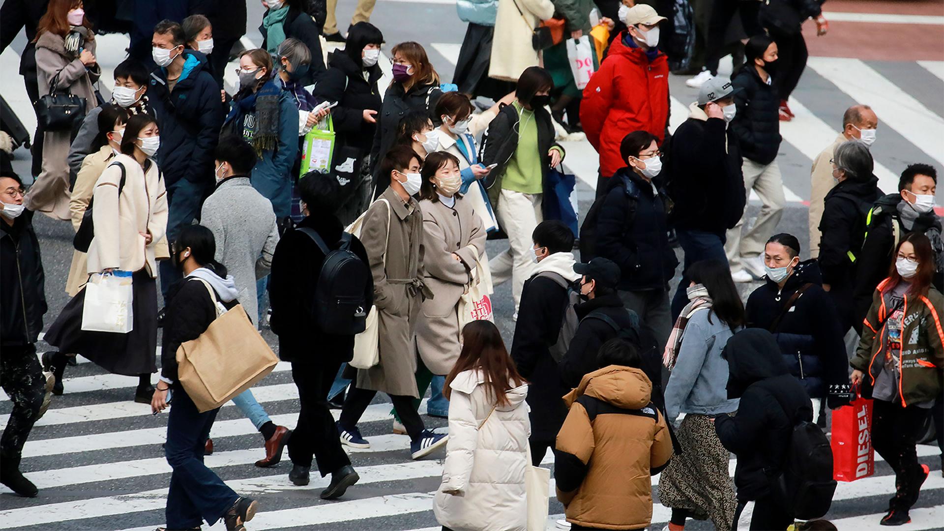 People wearing face masks to help protect against the spread of the coronavirus walk along the street in Tokyo, Japan