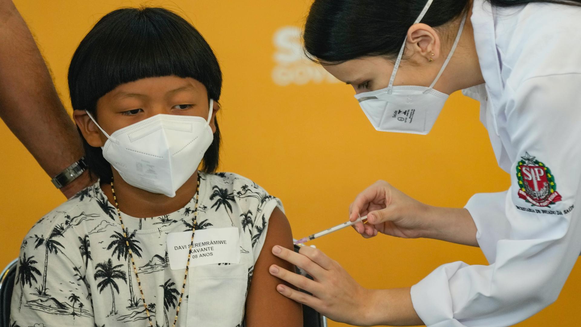 A health worker gives a shot of the Pfizer COVID-19 vaccine to 8-year-old Indigenous youth Davi Seremramiwe Xavante at the Hospital da Clinicas in São Paulo, Brazil, Jan. 14, 2022. 