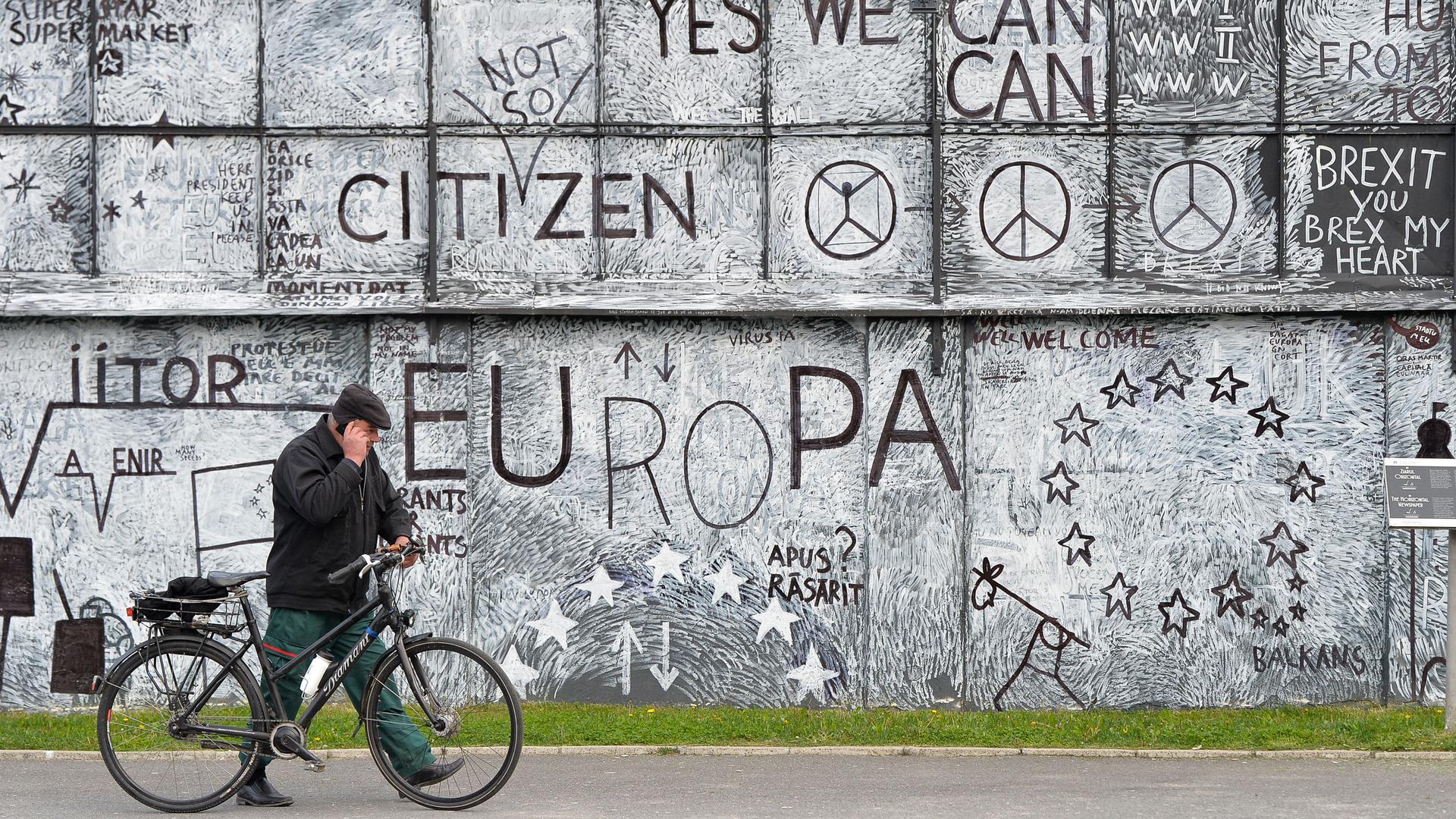 A man passes by a wall displaying an urban art project in the Transylvanian town of Sibiu, Romania, Wednesday, May 8, 2019. 