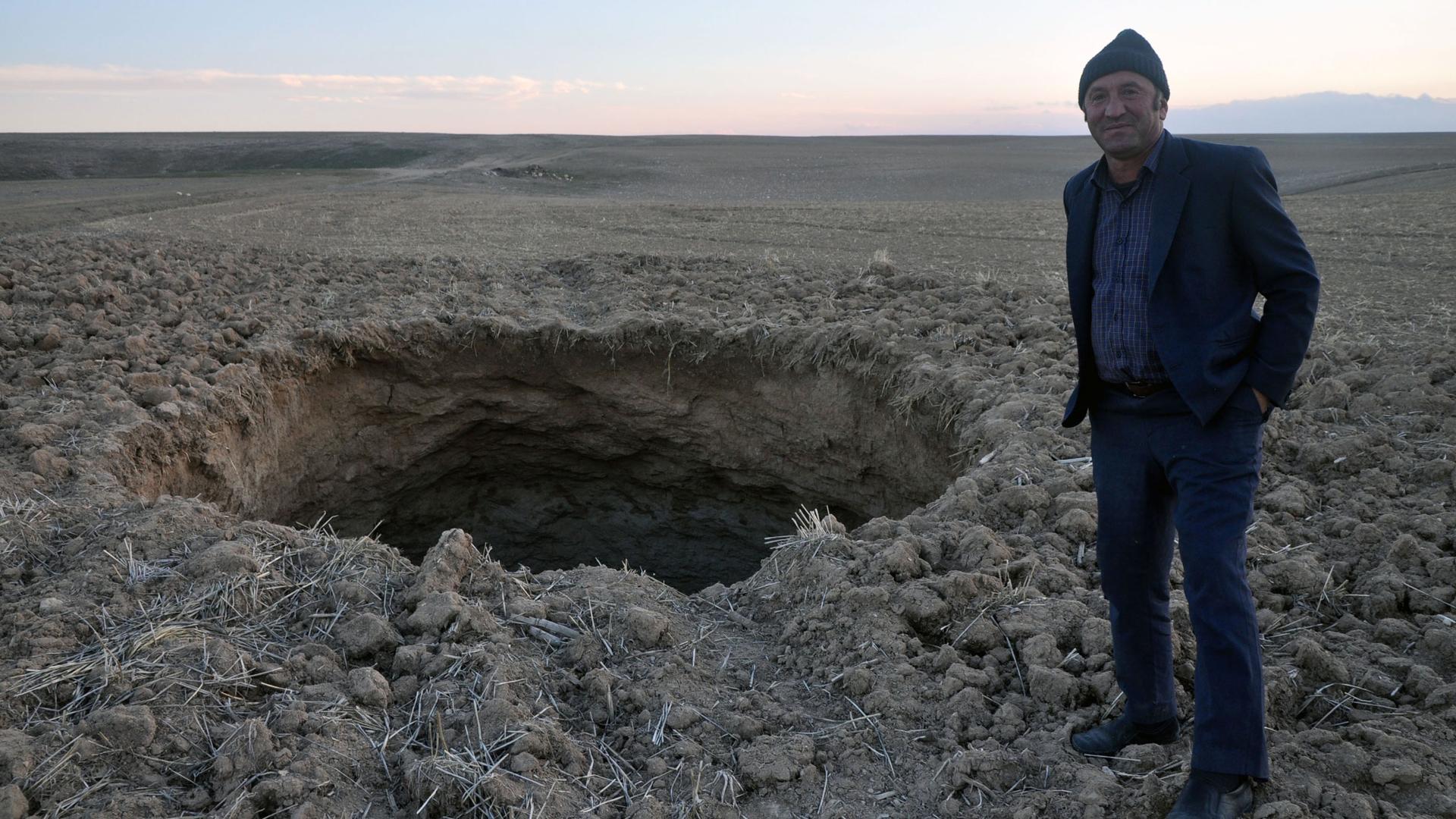 Cafer Ata stands beside a new sinkhole that opened up recently in a neighbor’s field.