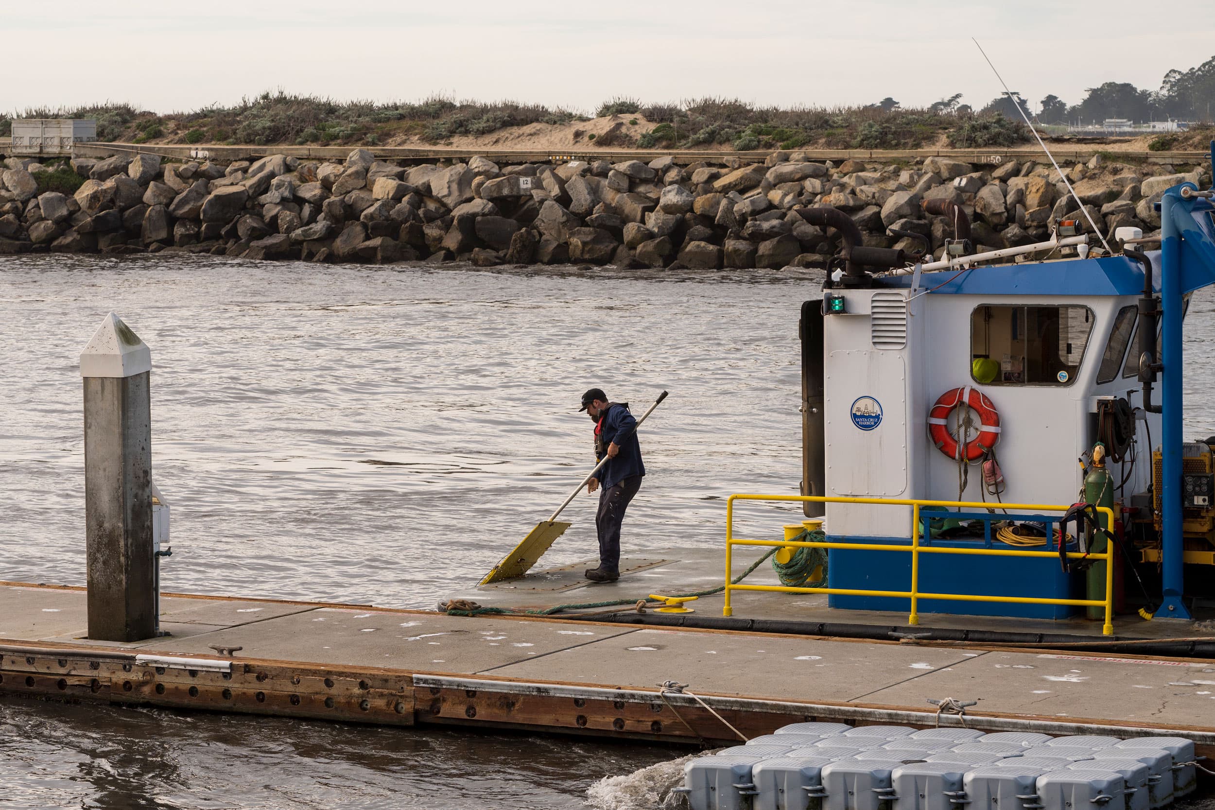 A harbor official pulls debris from rising waters out of Santa Cruz harbor in Santa Cruz, California, Saturday, Jan. 15, 2022.