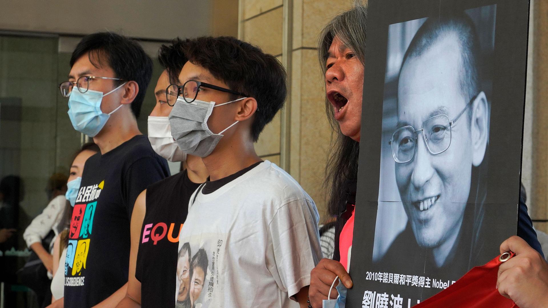 Activists shout slogans to mark anniversary of death of Chinese Nobel prize winner Liu Xiaobo outside a district court in Hong Kong, Monday, July 13, 2020. 