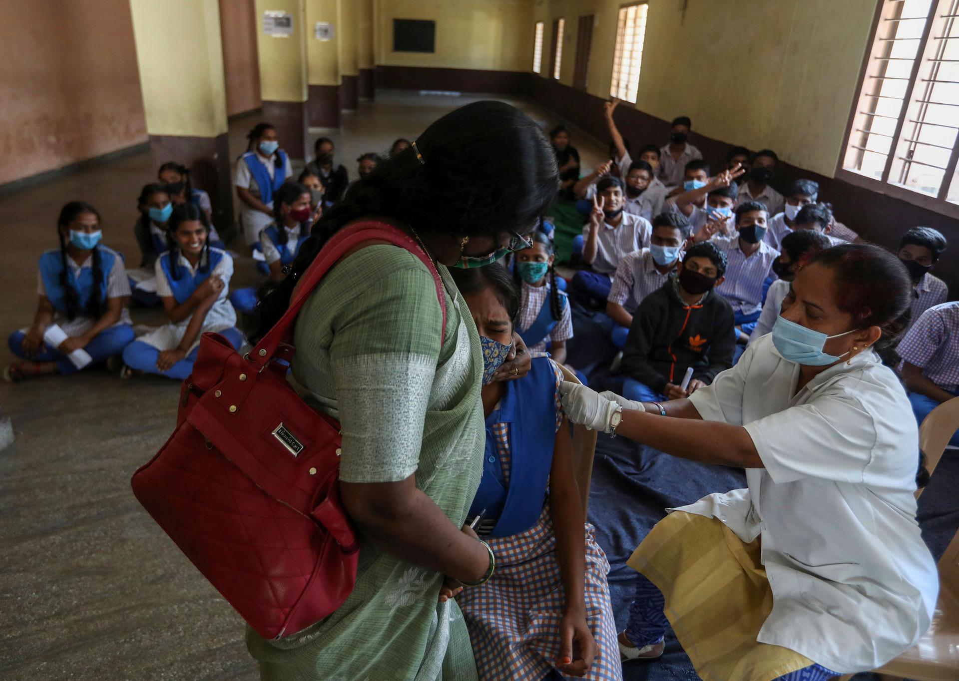 An Indian teen reacts as she receives Covaxin COVID-19 vaccine at a government school in Hyderabad, India, Thursday, Jan. 6, 2022. 