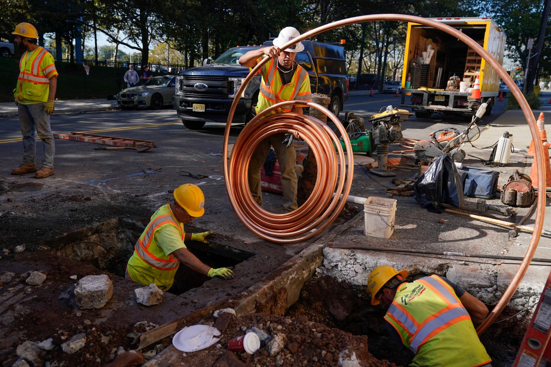 Workers prepare to replace older water pipes with a new copper one in Newark, New Jersey, Thursday, Oct. 21, 2021. 