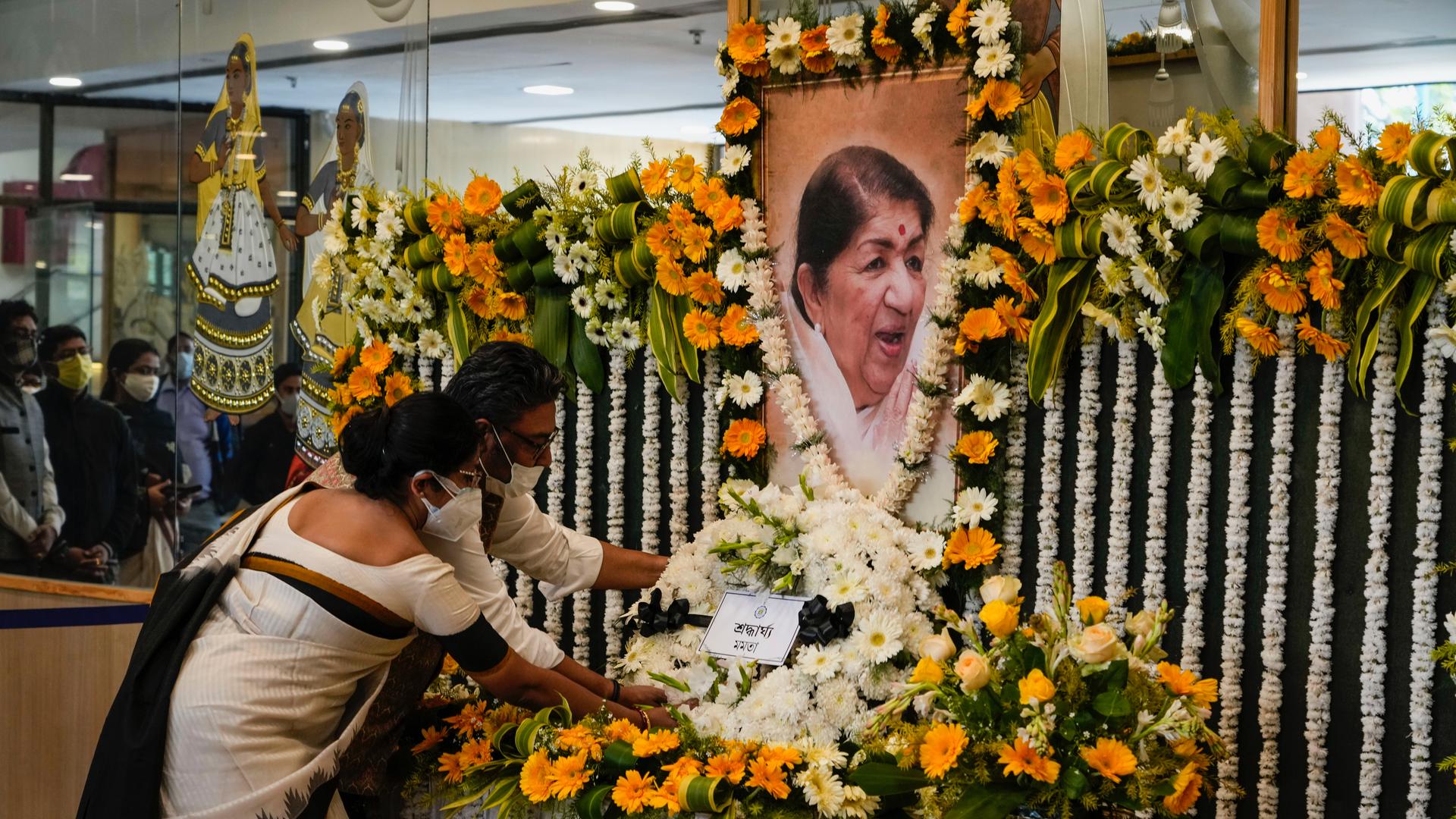 People pay tribute in front of a portrait of Lata Mangeshkar, the legendary singer placed on a decorated podium in Kolkata, India, Feb. 7, 2022. 