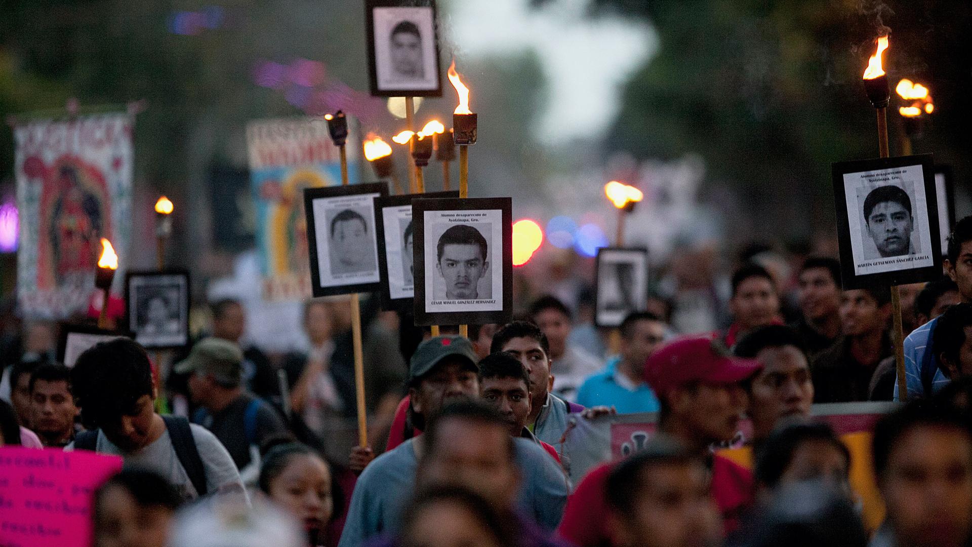 Relatives of the 43 missing students from the rural teachers college march holding pictures of their missing loved ones during a protest in Mexico City, Dec. 26, 2015. 