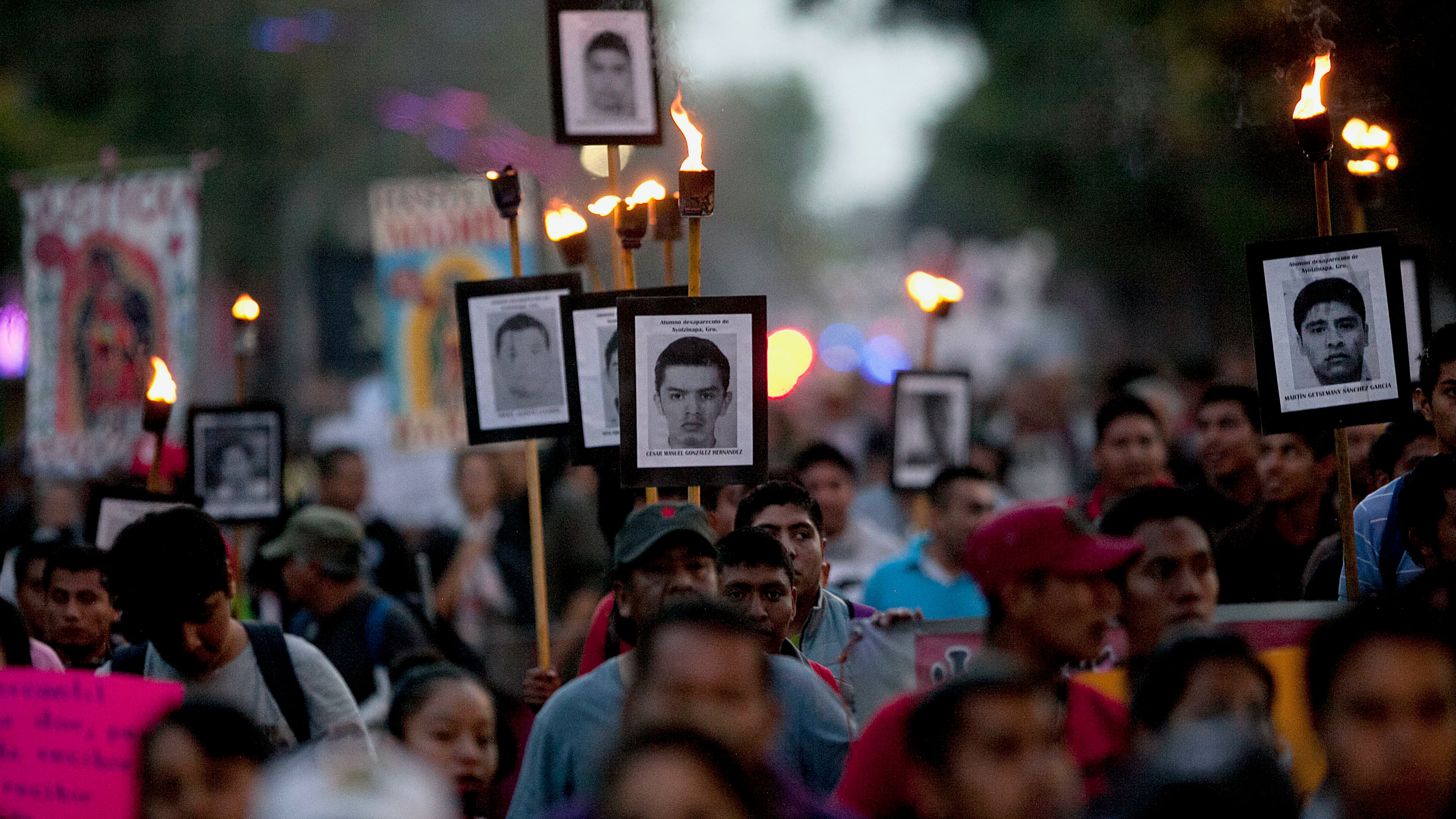 Relatives of the 43 missing students from the rural teachers college march holding pictures of their missing loved ones during a protest in Mexico City, Dec. 26, 2015.