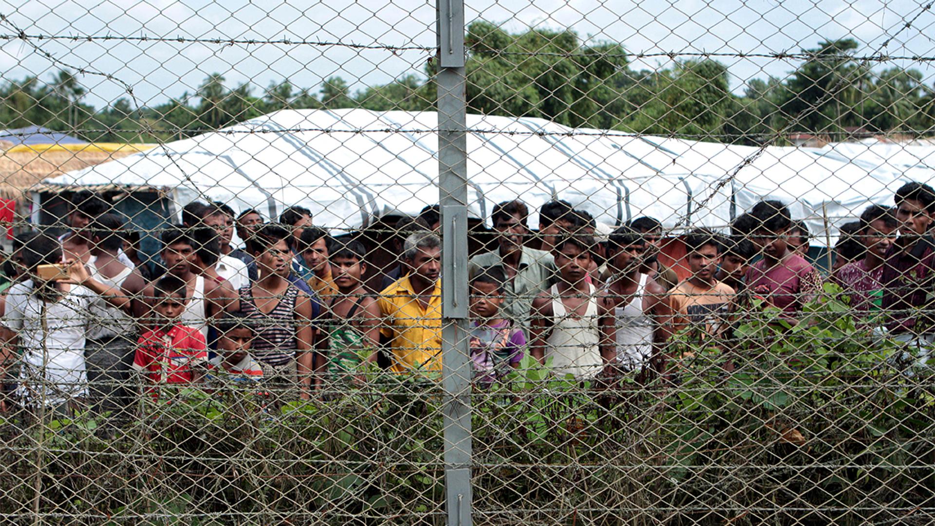 Rohingya refugees gather near a fence during a government organized media tour, to a no-man's land between Myanmar and Bangladesh, near Taungpyolatyar village, Maung Daw, northern Rakhine State, Myanmar