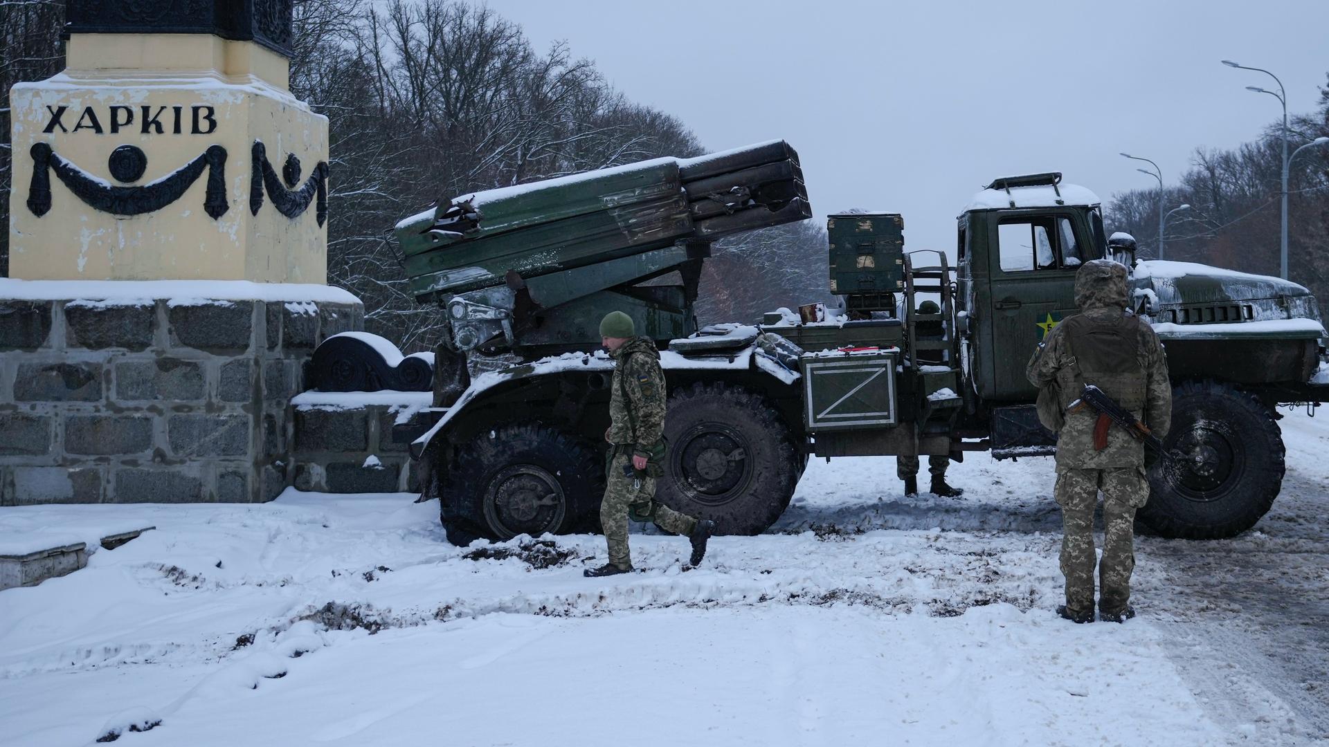 Ukrainian servicemen walk by a deactivated Russian military multiple rocket launcher on the outskirts of Kharkiv, Ukraine, Feb. 25, 2022. Russian troops bore down on Ukraine's capital Friday, with gunfire and explosions resonating ever closer to the gover