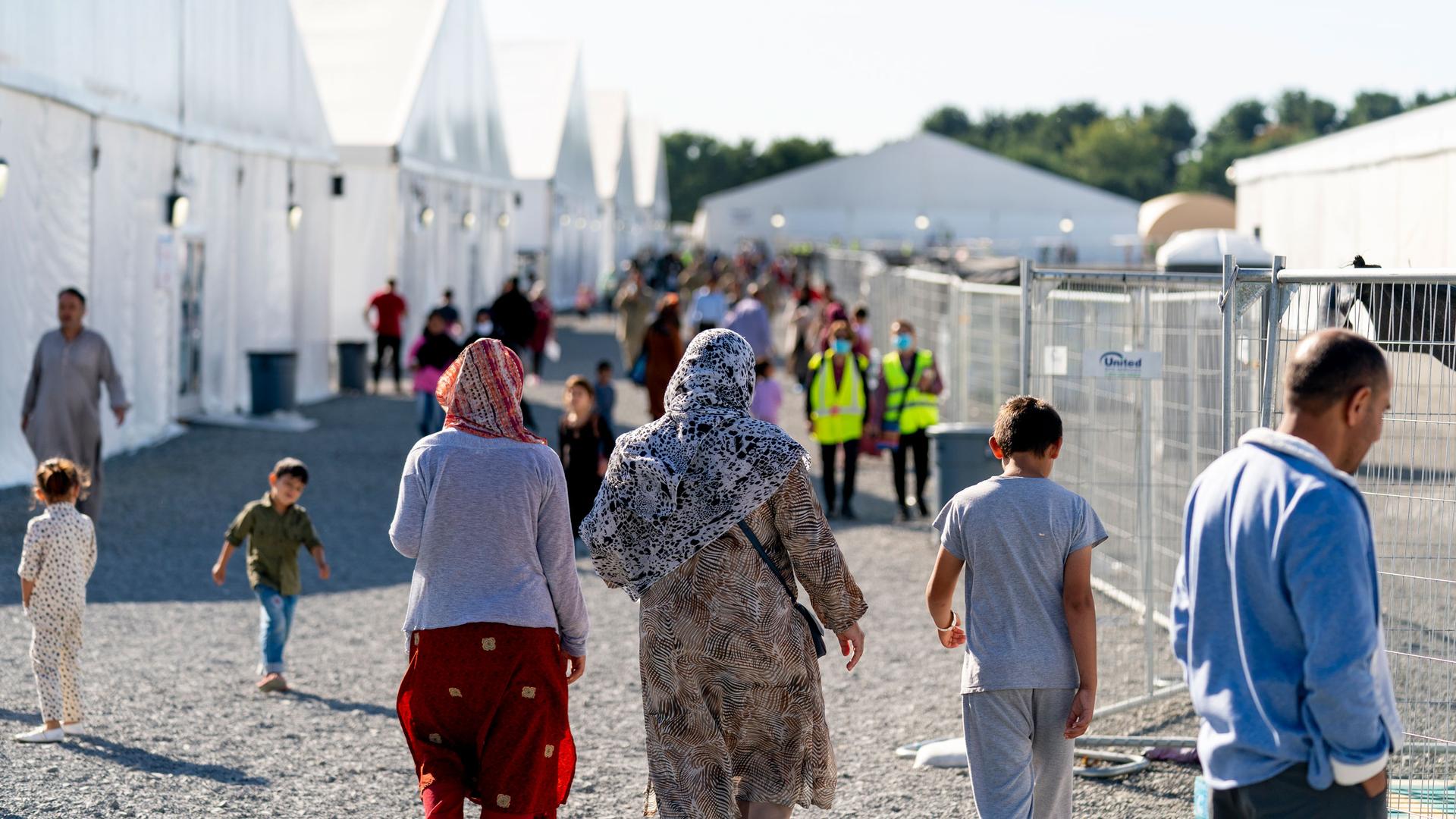 Afghan refugees walk through an Afghan refugee camp at Joint Base McGuire Dix Lakehurst, New Jersey, on Sept. 27, 2021. 