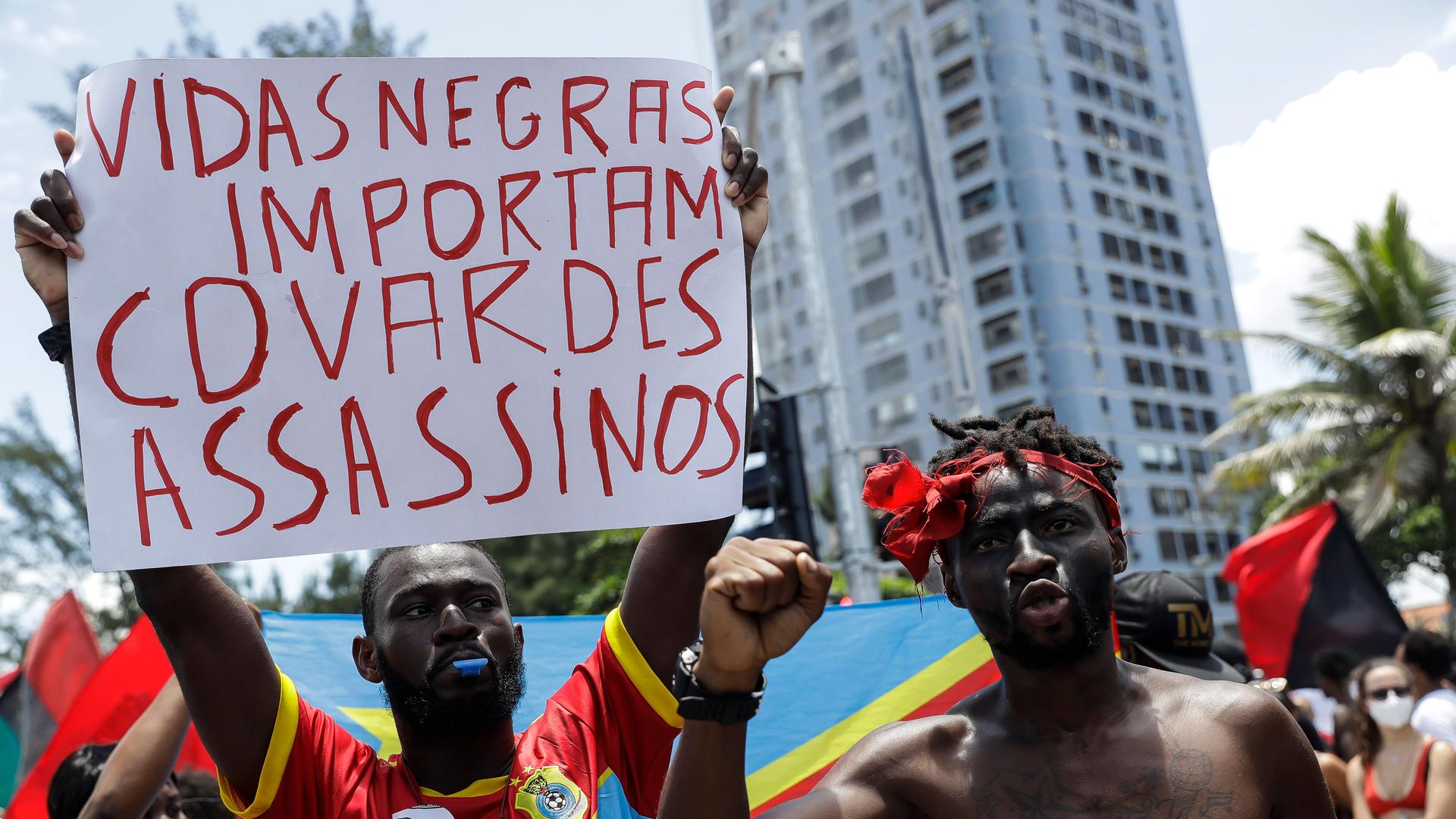 A friend of 24 year-old Congolese immigrant Moïse Mugenyi Kabagambe, holds up a sign during a protest to demand justice for his violent death, at Barra da Tijuca beach, in Rio de Janeiro, Brazil, Saturday, Feb. 5, 2022. 