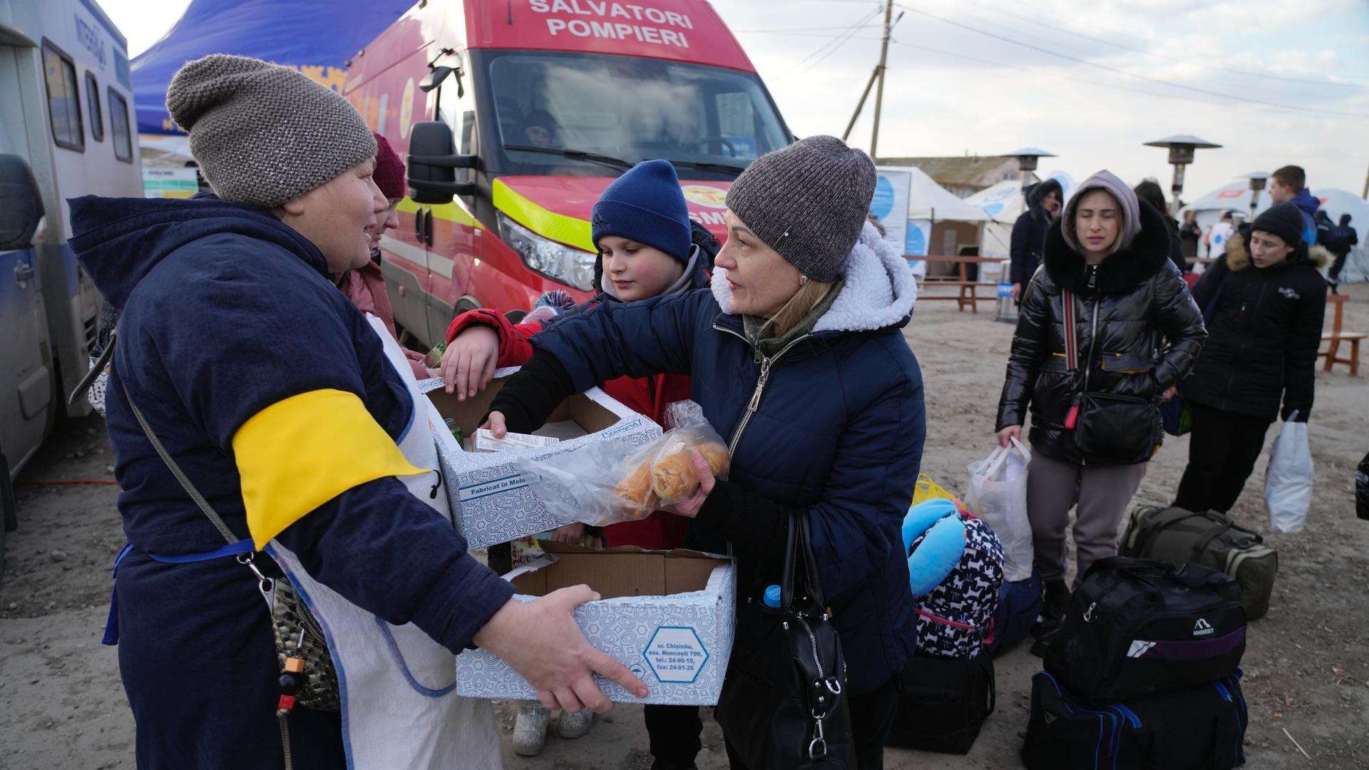 A Moldovan volunteer distributes food to refugees who are leaving to Romania after fleeing from Ukraine, at the border crossing in Palanca, Moldova, March 17, 2022.