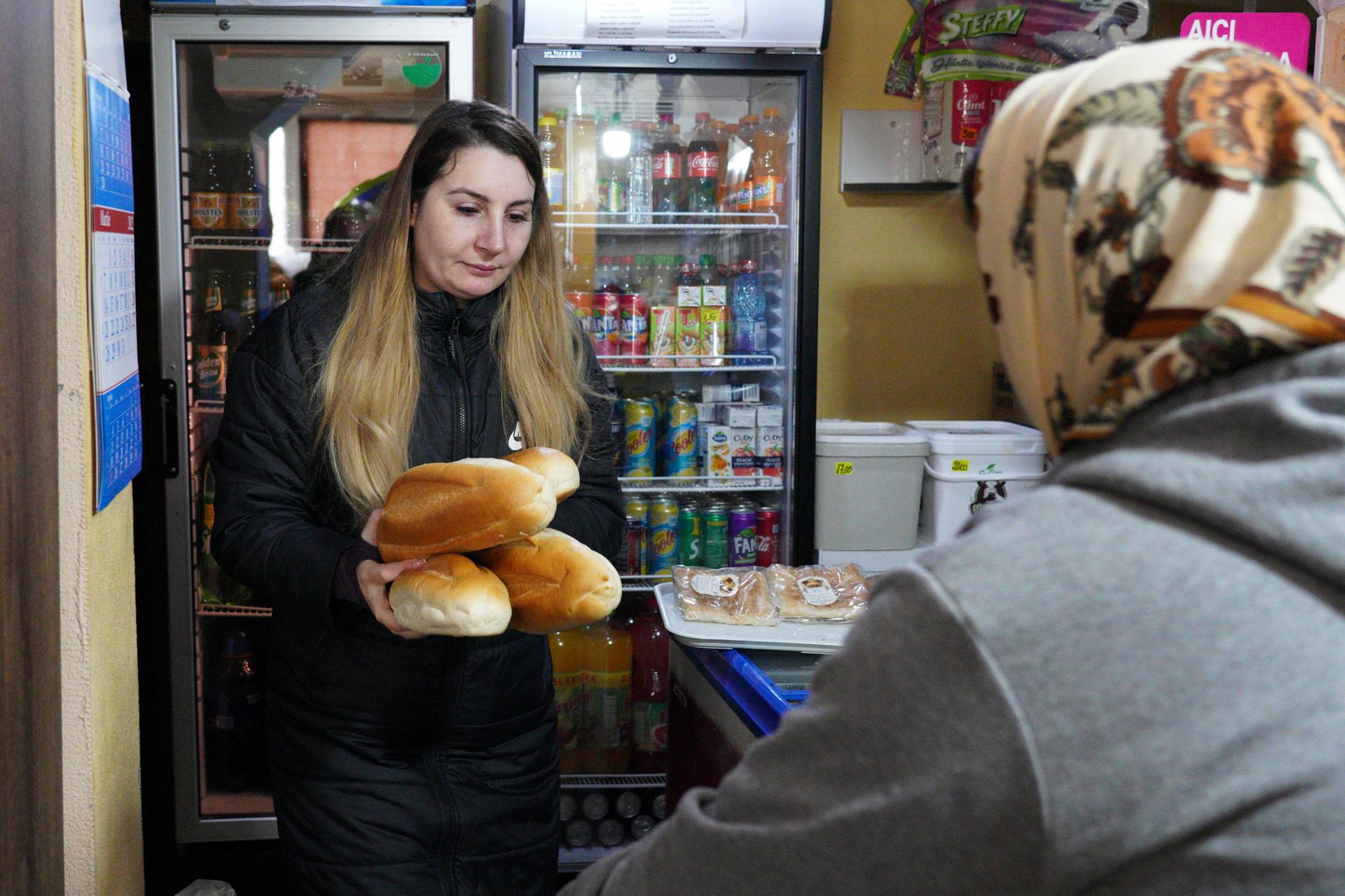 Christina Alexandro takes care of her parents' shop on a visit to her hometown of Deveselu. Like many working-age adults from rural Romania, Alexandro moved to the United Kingdom for work.