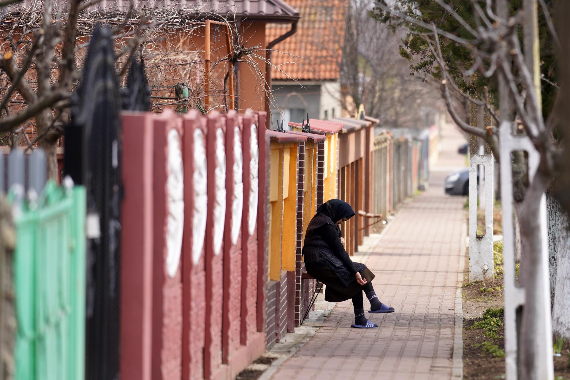 A woman sits outside her home in the village of Deveselu. Like many rural Romanian towns, the population is largely elderly people and their grandchildren. Many working-age adults have moved to western Europe for work.