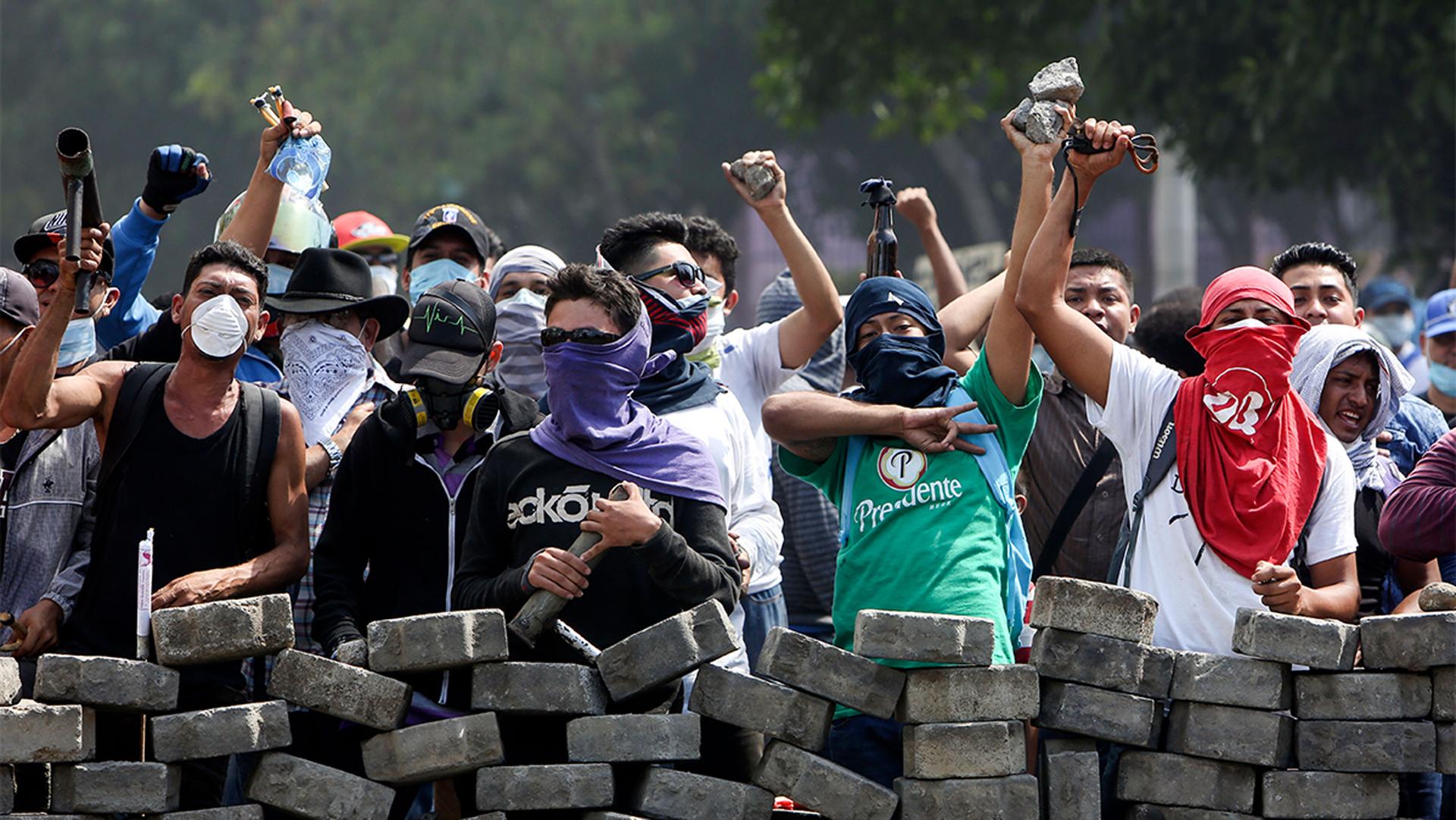 Protesters yell from behind the roadblock they erected as they face off with security forces near the University Politecnica de Nicaragua, UPOLI, in Managua, Nicaragua