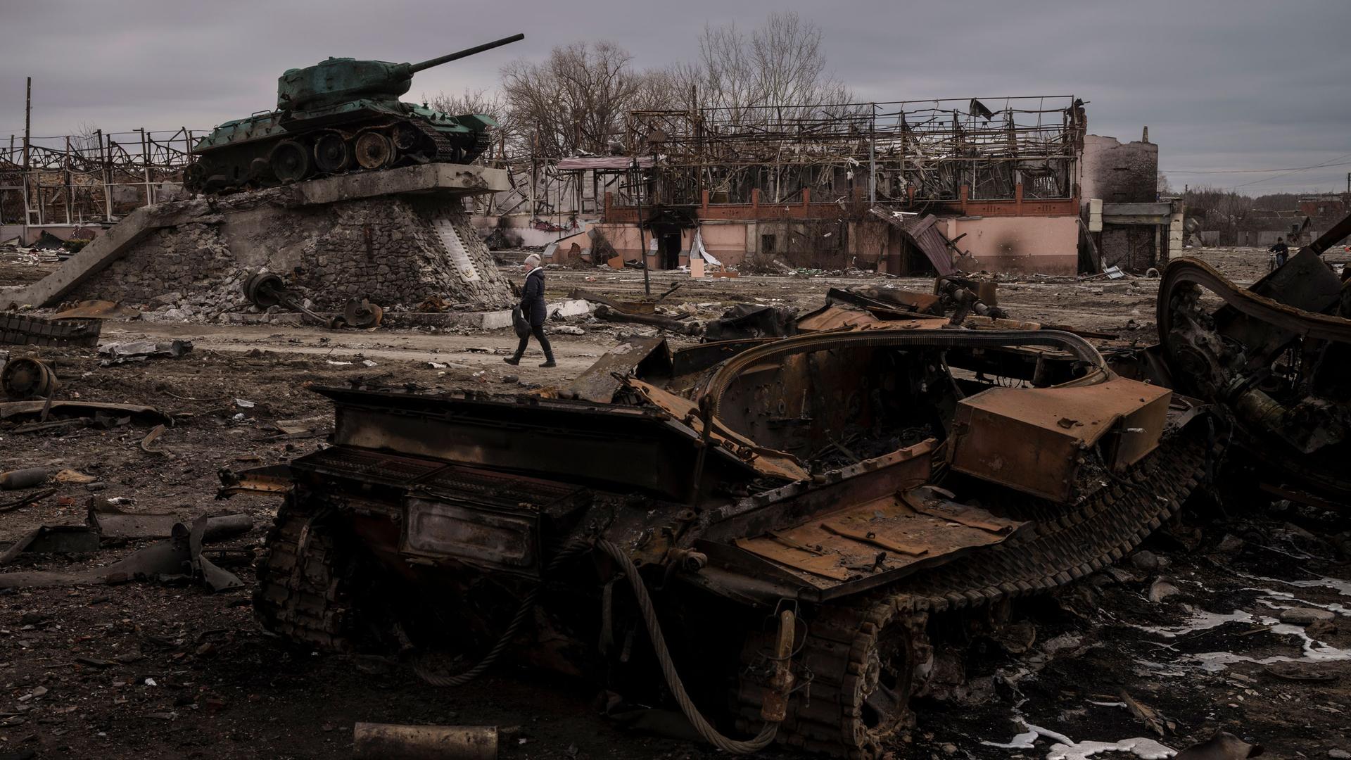 A woman walks past a destroyed tank in the town of Trostsyanets, Ukraine, Monday, March 28, 2022.