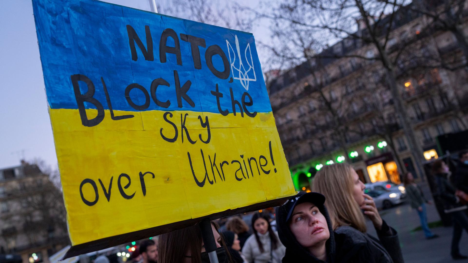 A protester calls for on NATO to enforce a no-fly zone over the Ukraine during a demonstration in Paris, France, Saturday, Feb. 26, 2022.