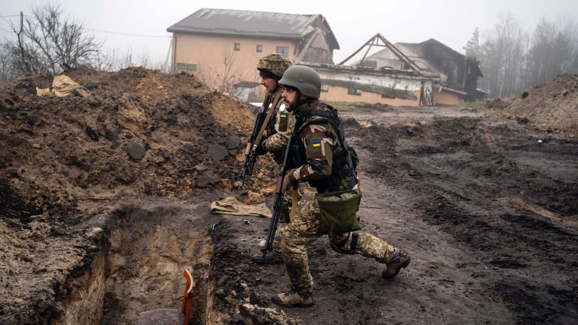 Ukrainian soldiers inspect trenches used by Russian soldiers during the occupation of villages on the outskirts of Kyiv, Ukraine, April 1, 2022. 