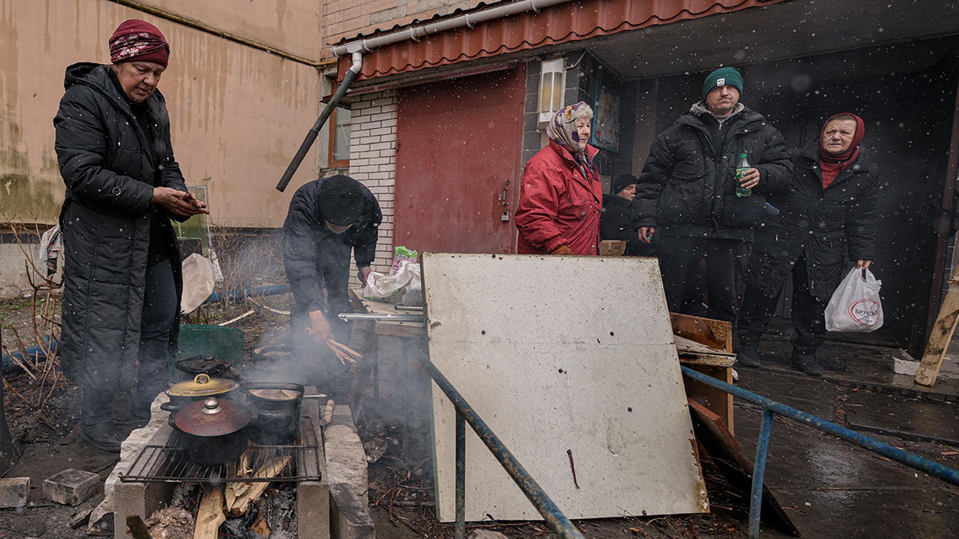 People cook on an open fire outside an apartment building which had no electricity, water or gas since the beginning of the Russian invasion in Bucha, UkraineVadim Ghirda/AP