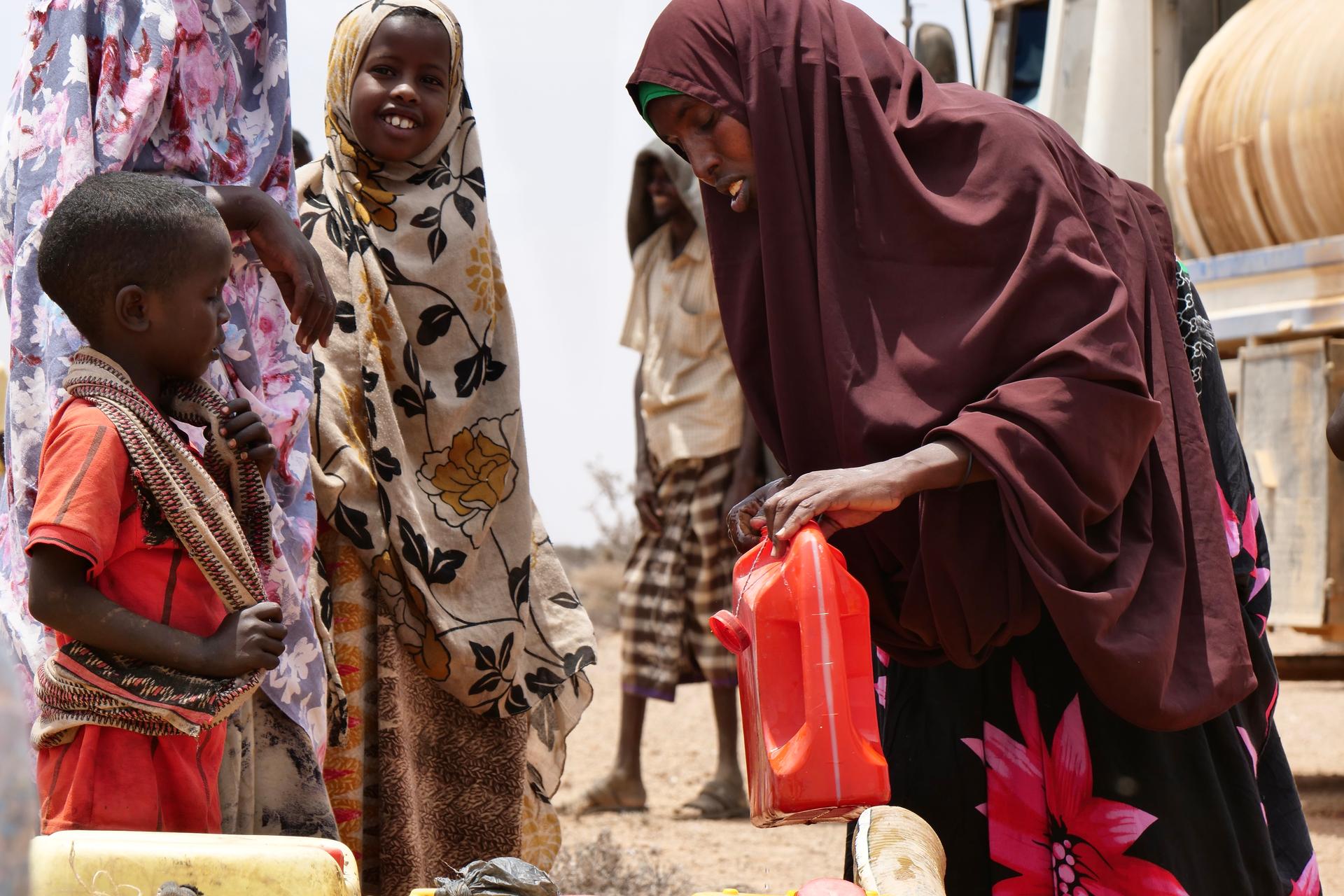 A woman collects water being distributed at the Kuresyon village in Galkayo, Somalia