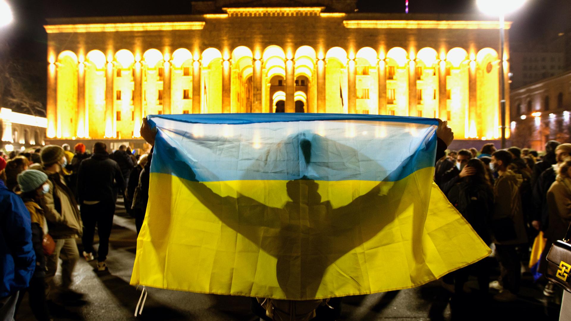 demonstrator holding the Ukraine flag around their body