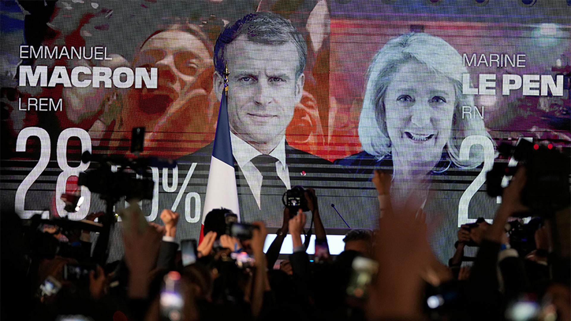 A screen shows French President Emmanuel Macron and far-right candidate Marine Le Pen at her election day headquarters, in Paris